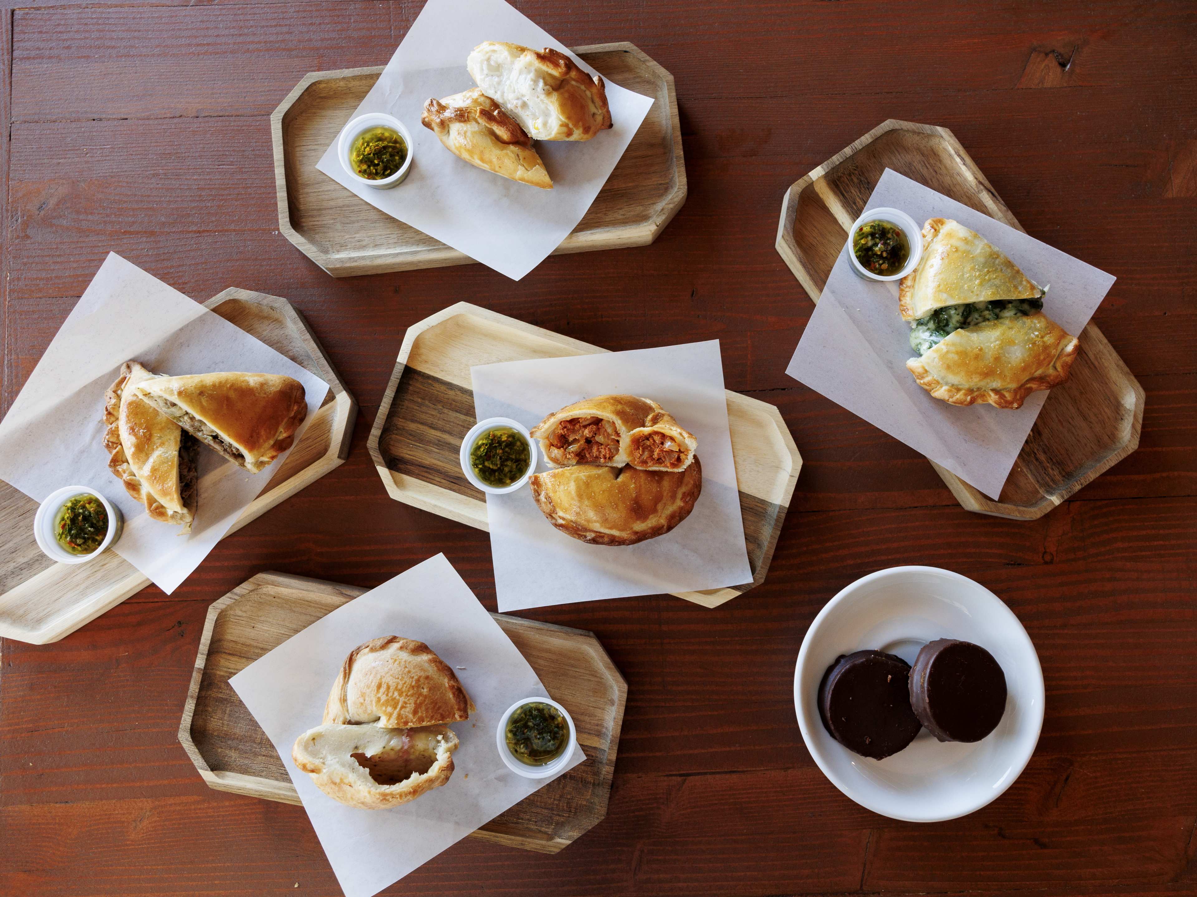 Assortment of empanadas cut in half, as well as chocolate alfajores