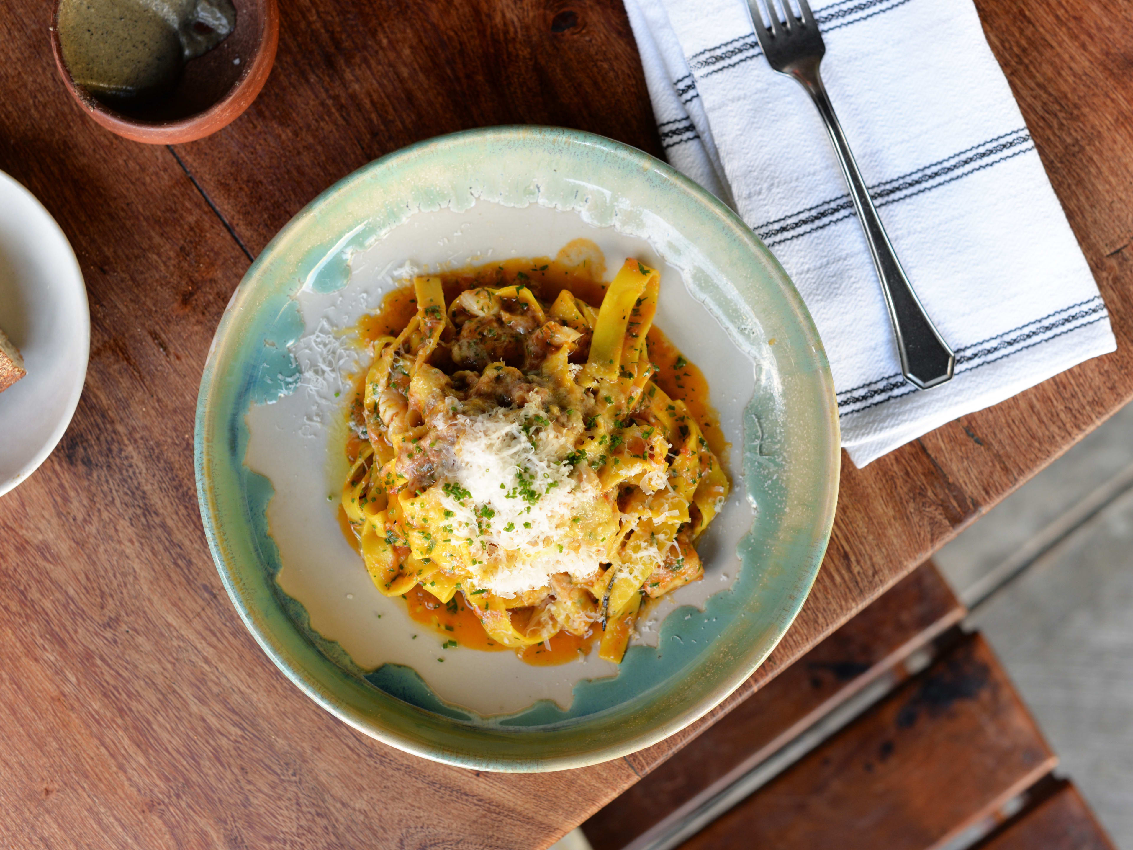 Seafood pasta dish on wooden table at Maximo Bistrot