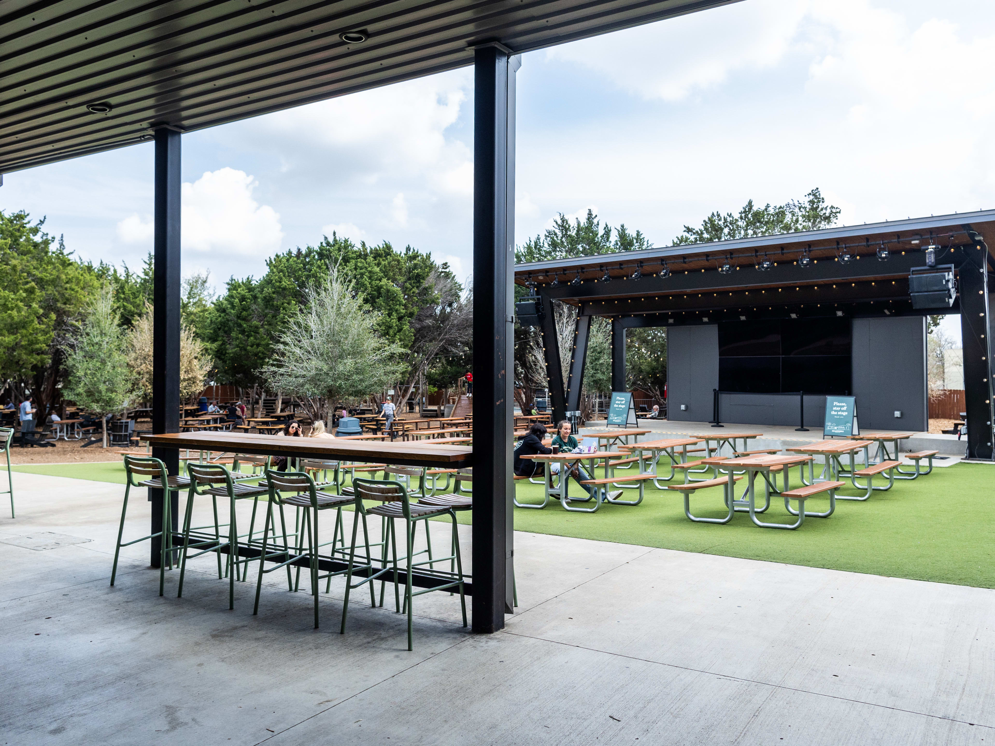 a patio with a stage and picnic tables