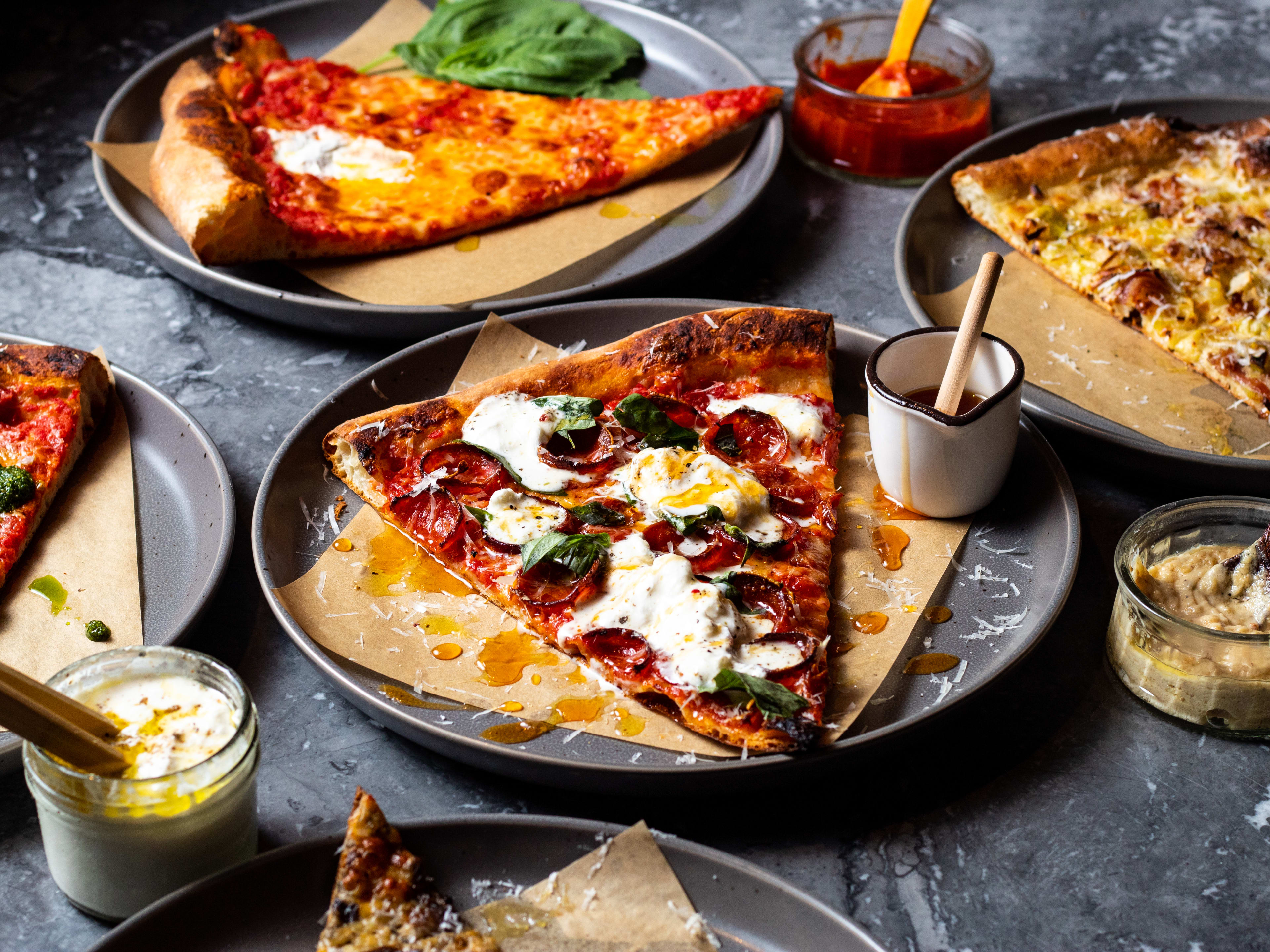 spread of pizza slices with dips and sauces in jars