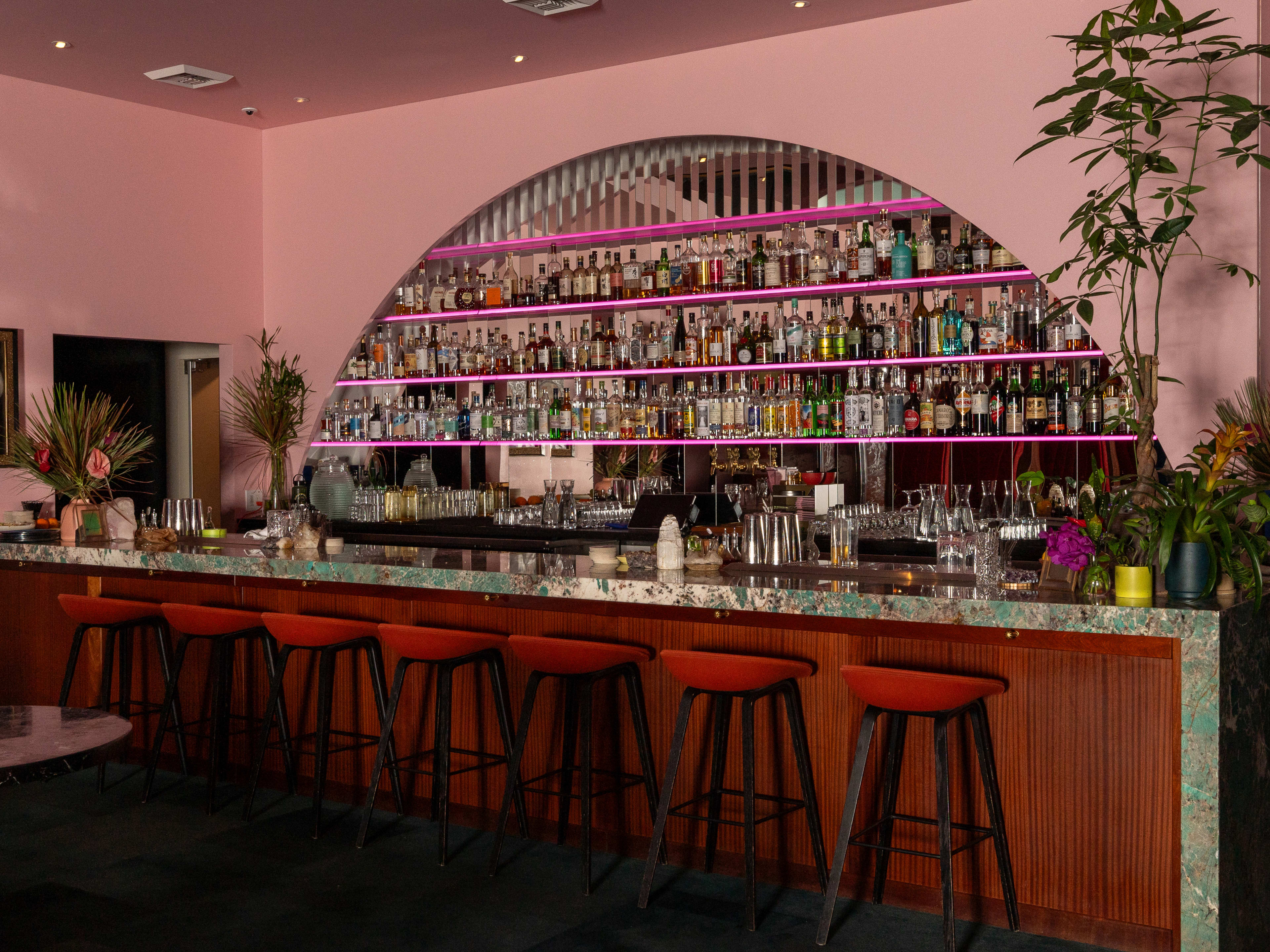 bar area with bar stools and arched liquor shelves