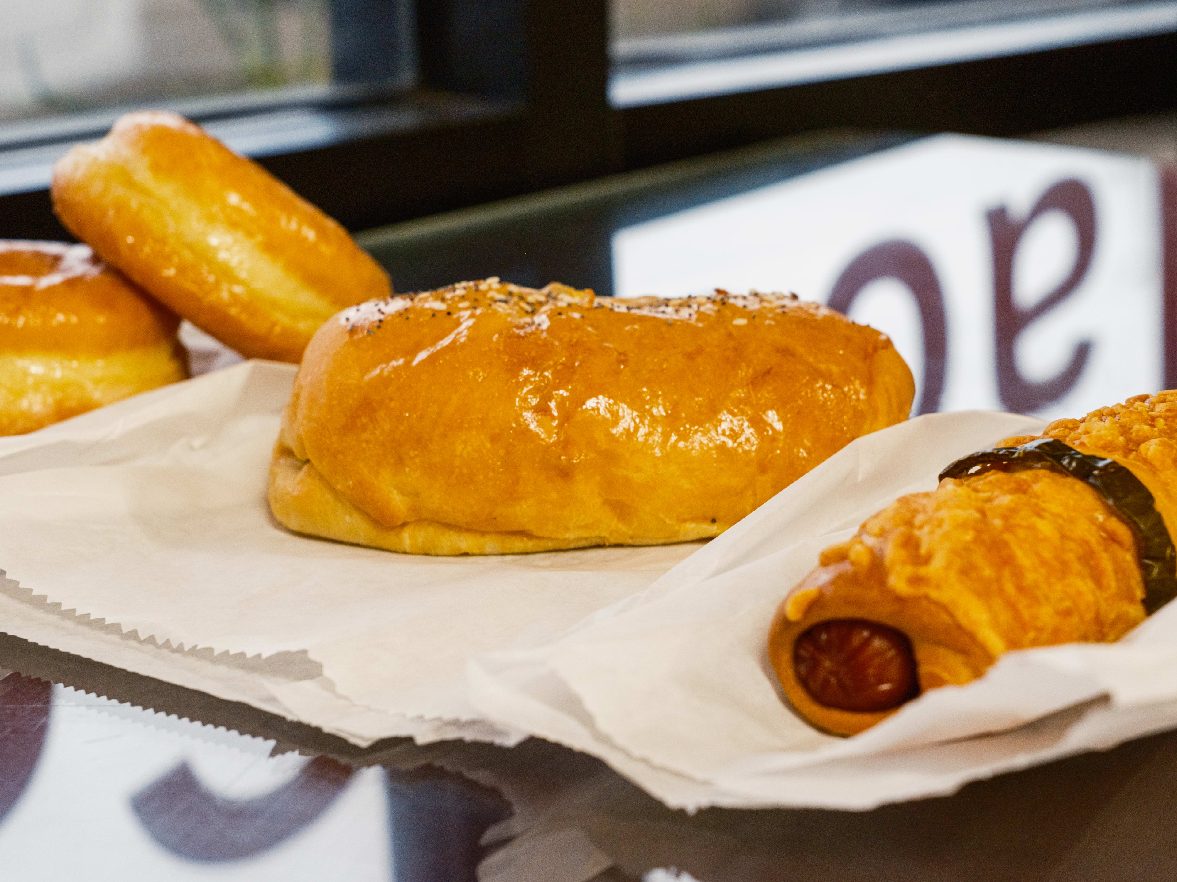 A glased donut, boudin kolache and biscuit kolache on a window counter at Mr. Donut.