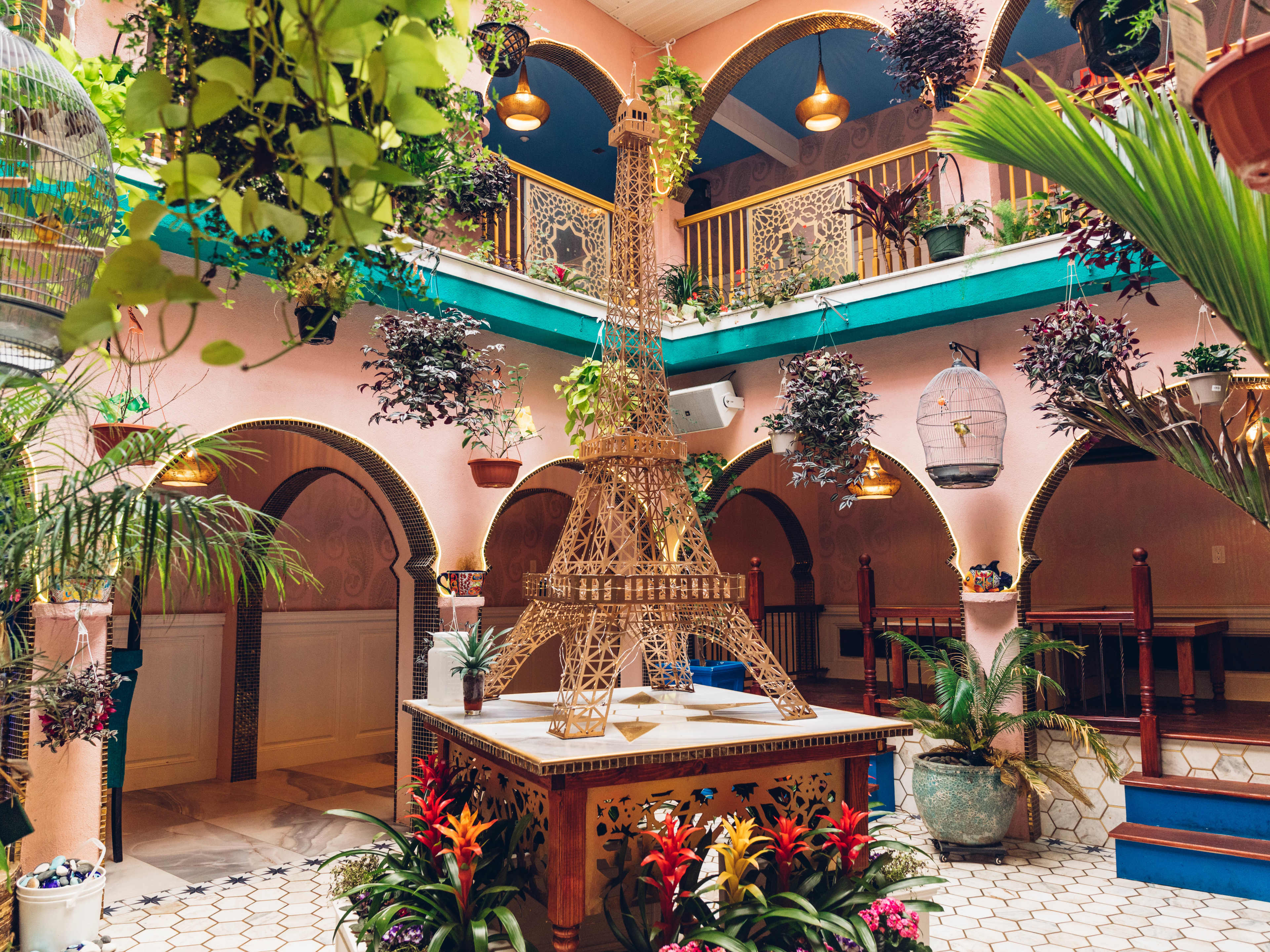A pink courtyard with a model Eiffel Tower and tropical plants.
