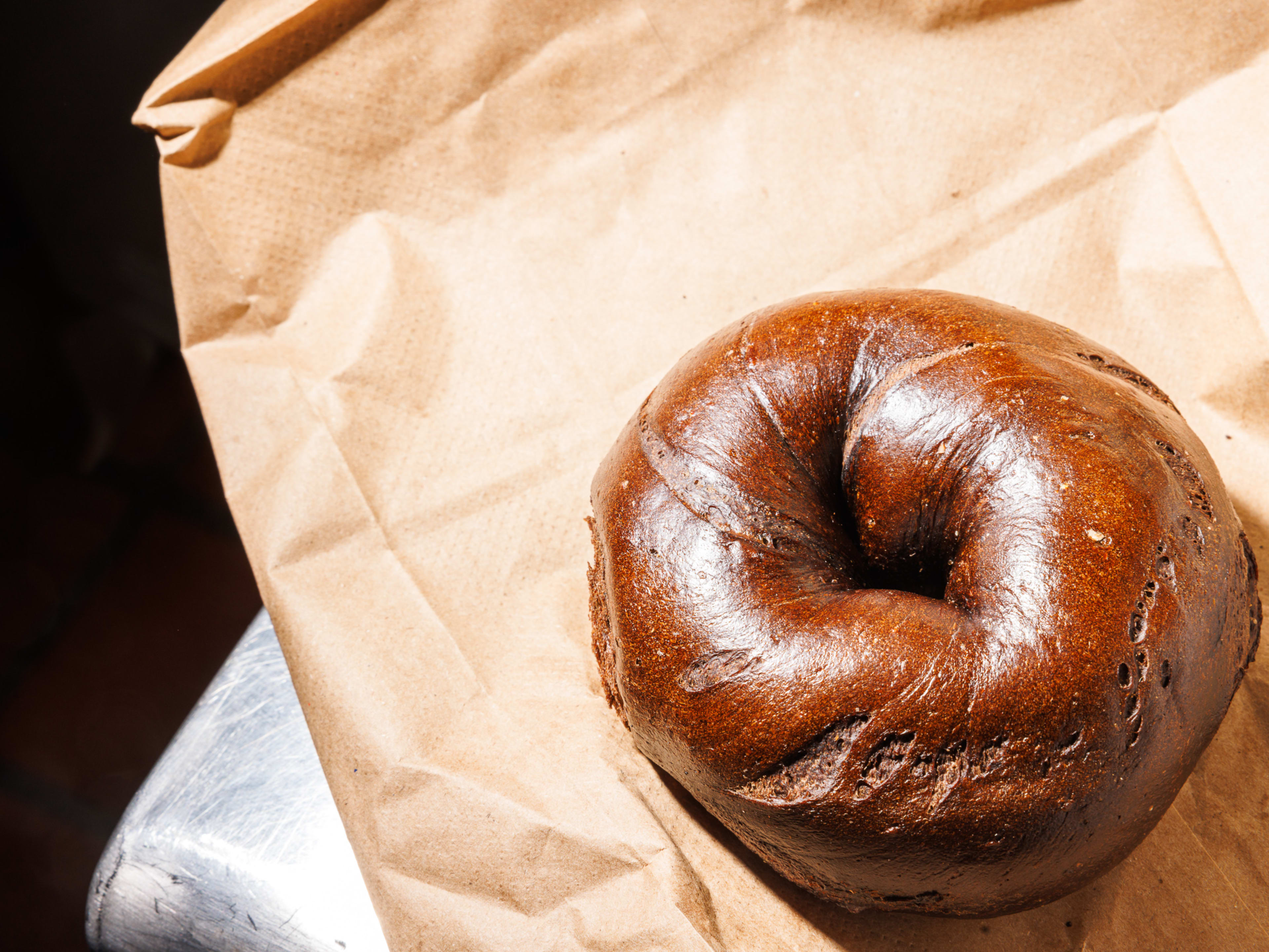 A pumpernickel bagel on a brown bag.