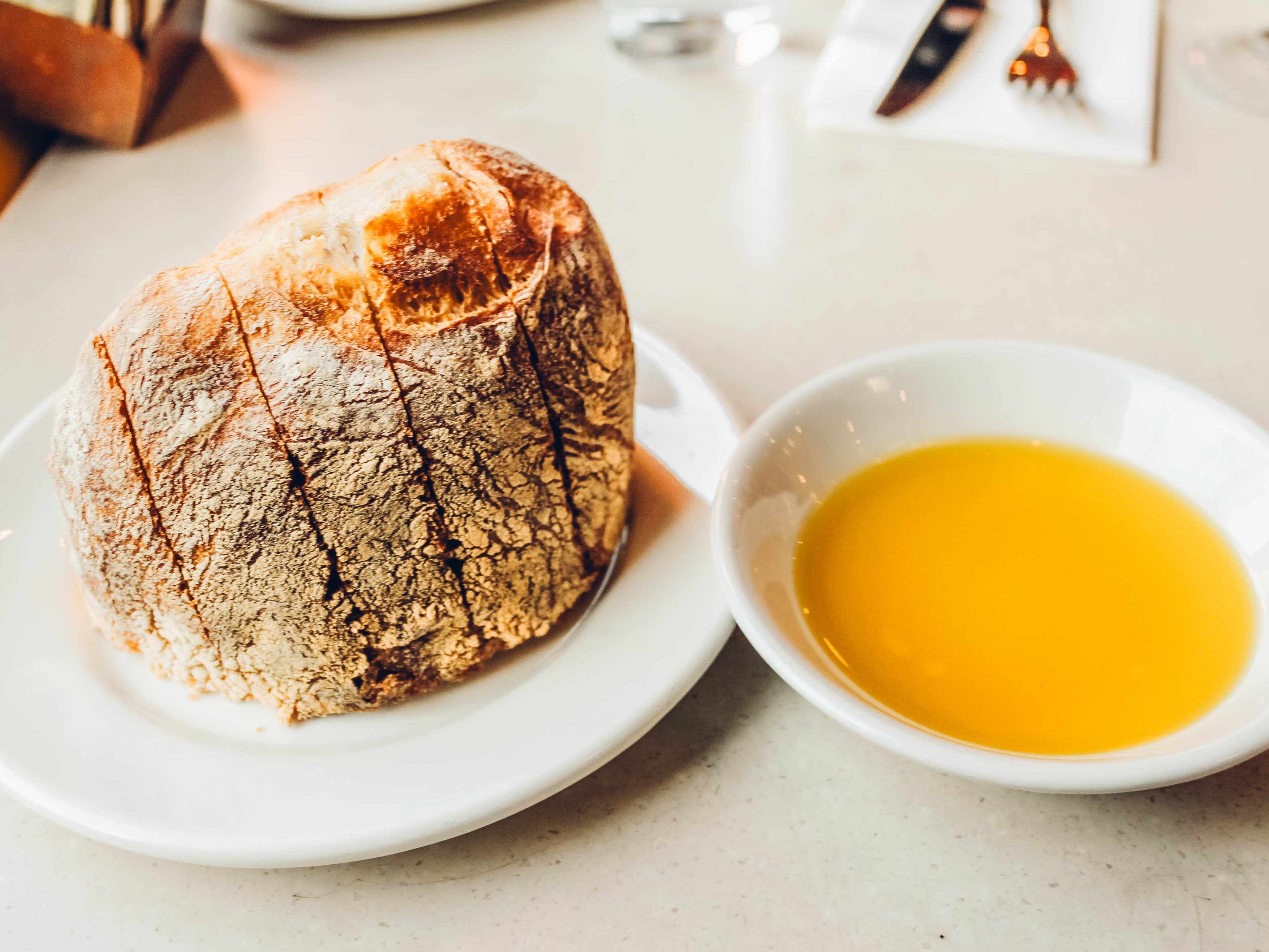 A plate of bread with a pool of olive oil on the side.