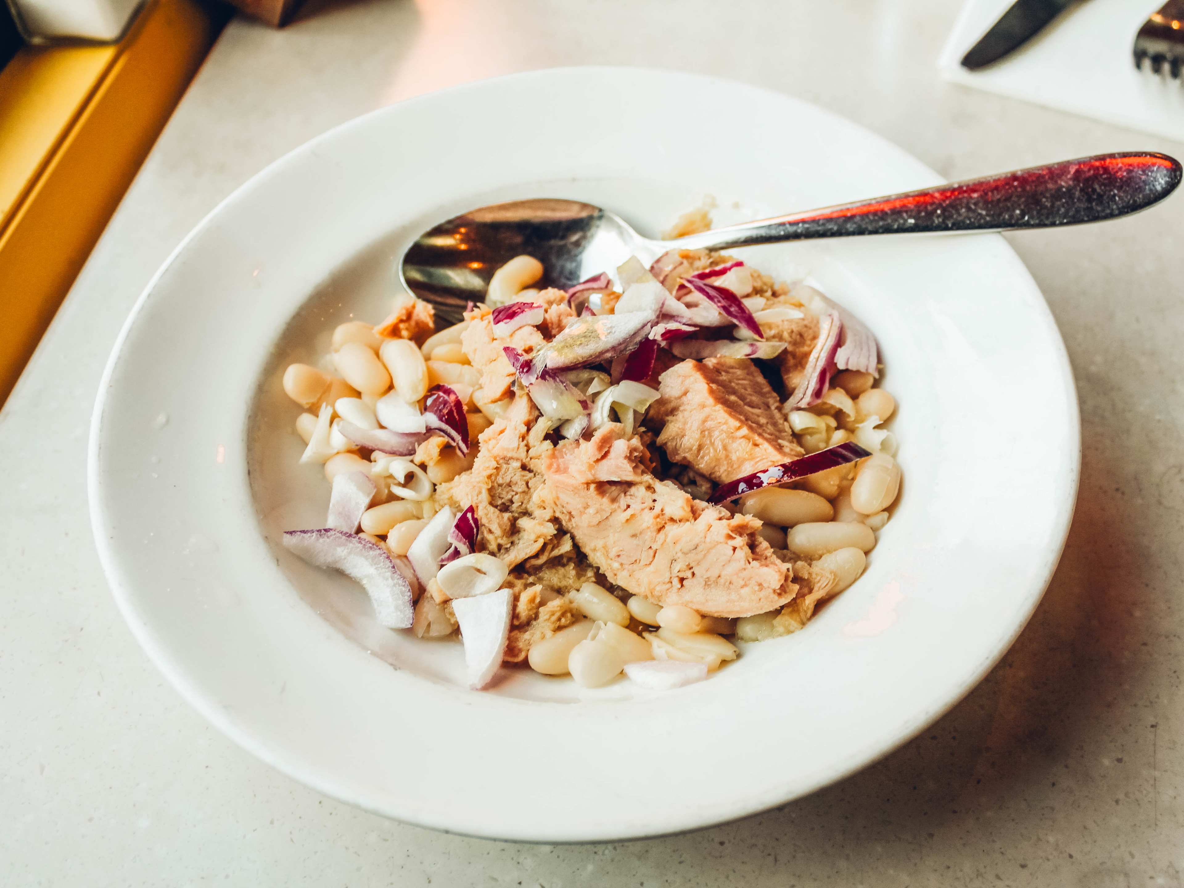 Tuna, beans, and red onion in a bowl.