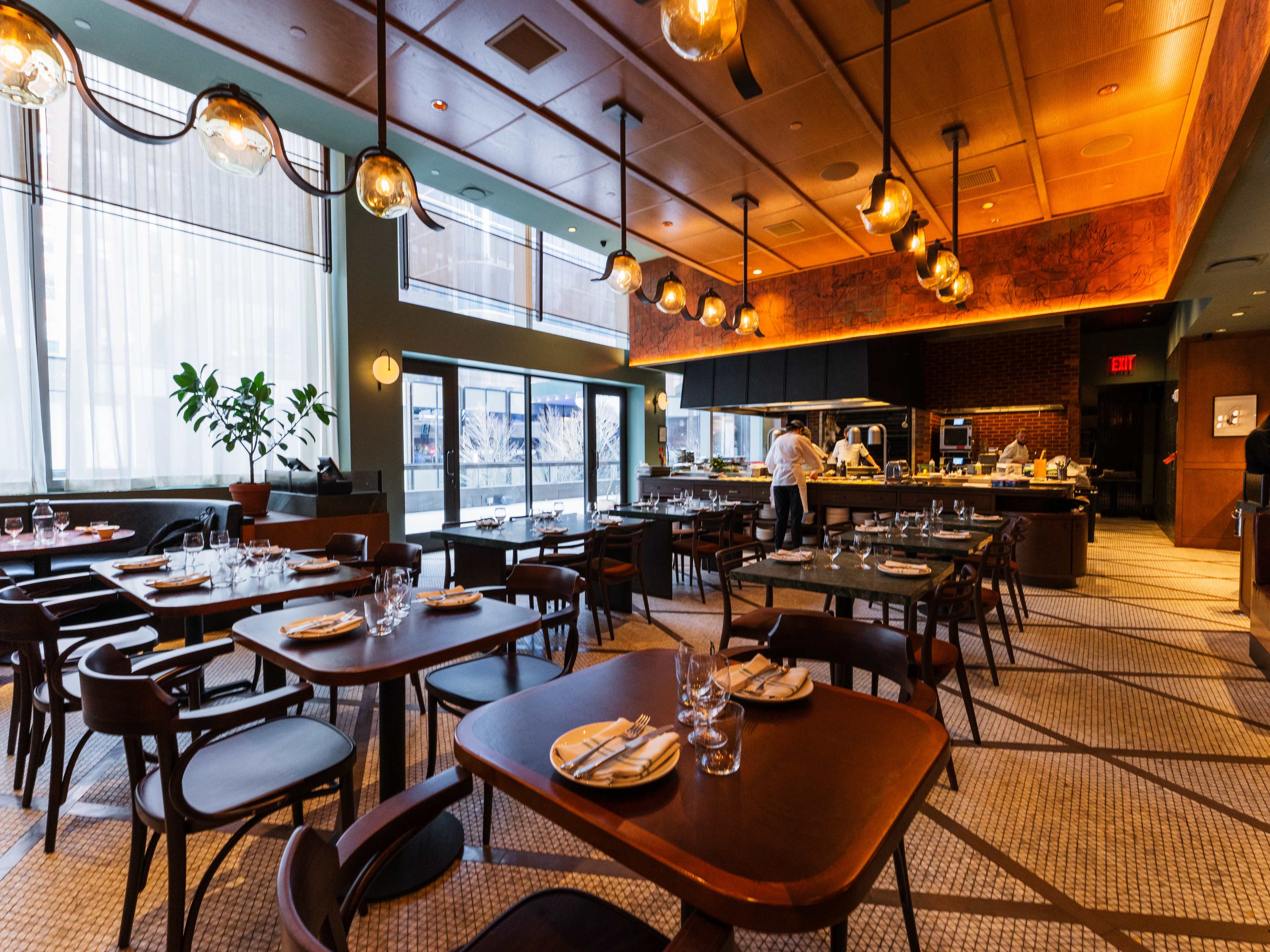 The interior of Ci Siamo with dark wooden tables, hanging pendant lights and natural accents.