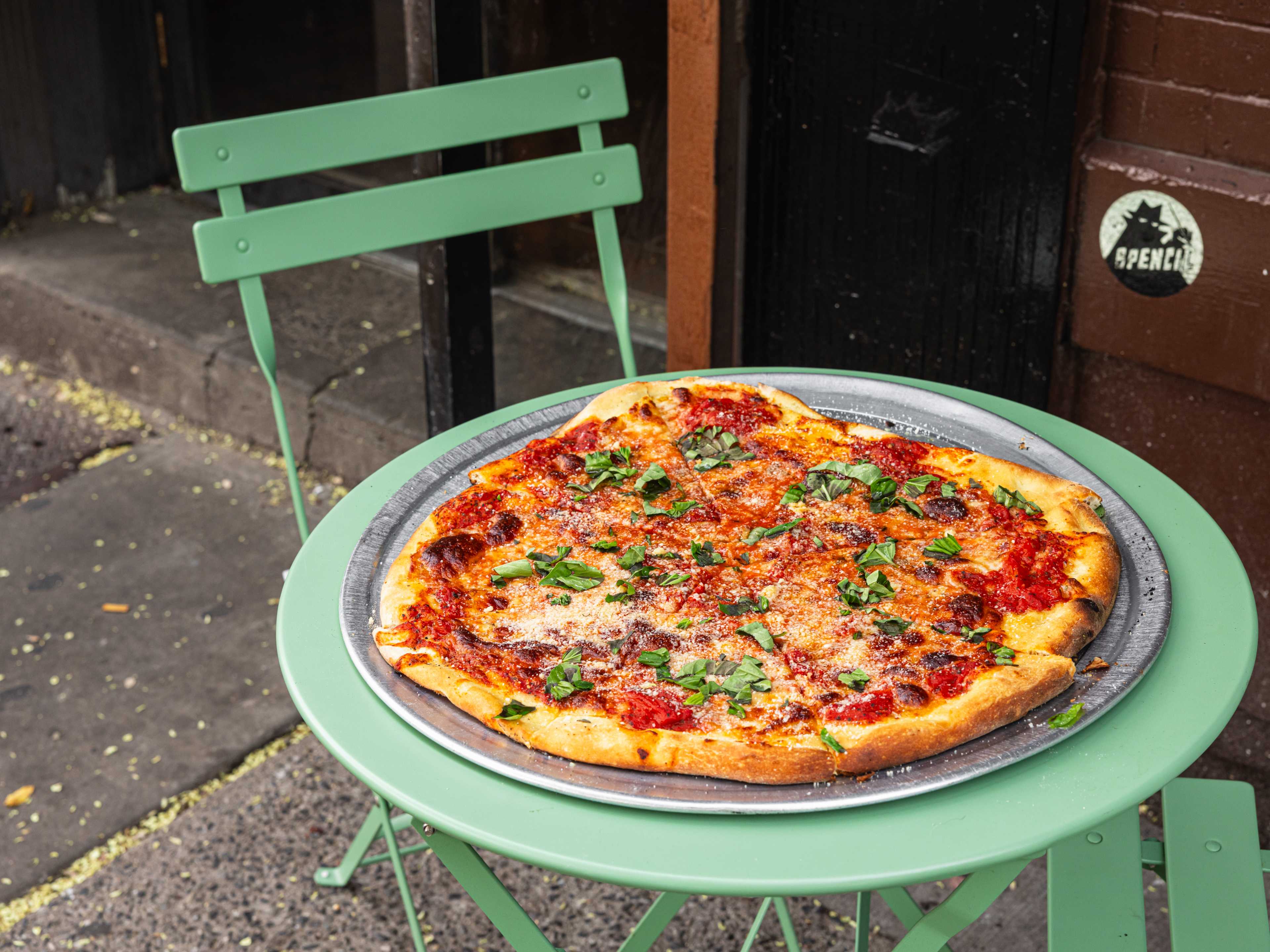 The regular pie from Di Fara Pizza on a round green table outside.