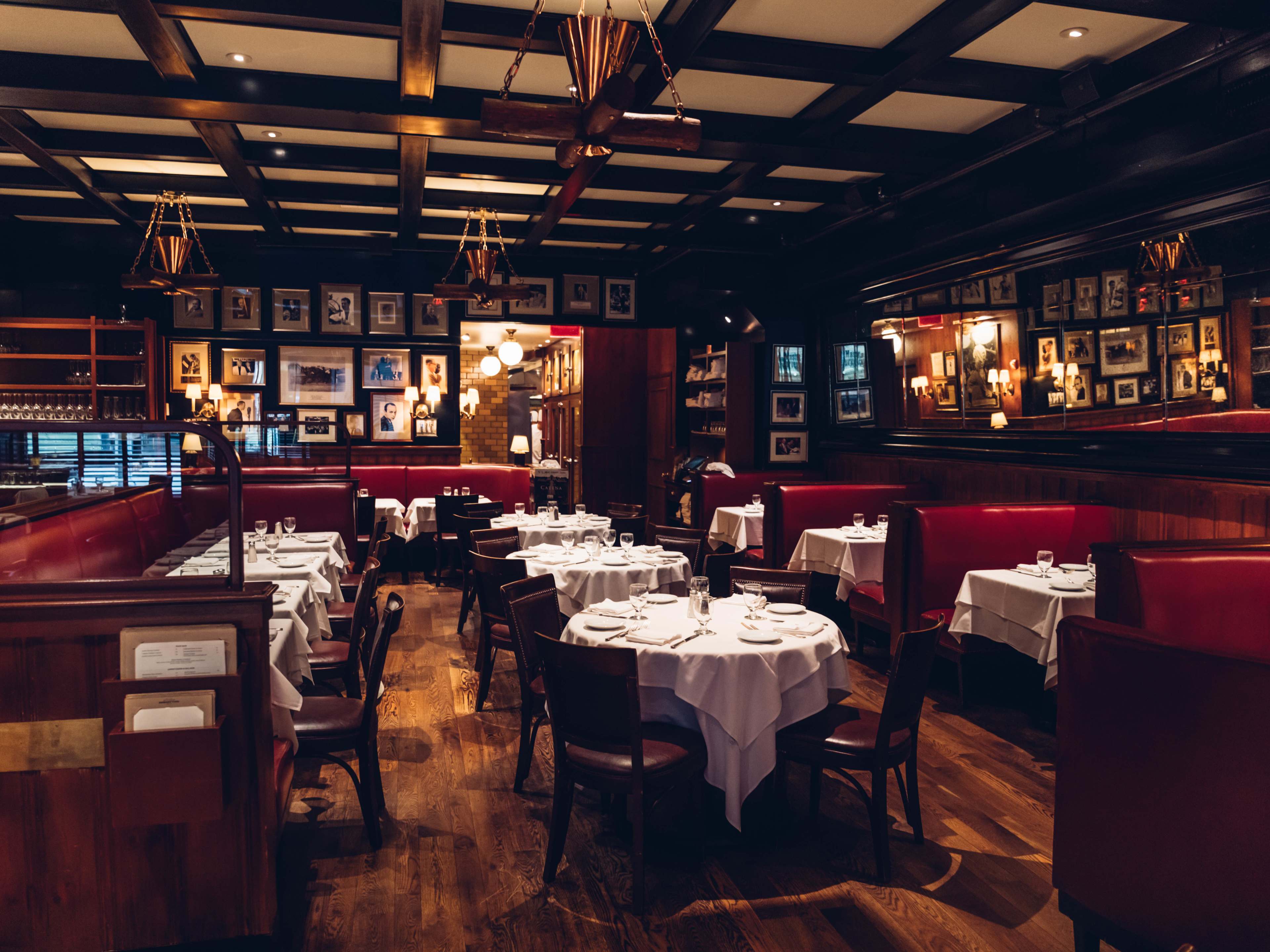 A dark dining room with big booths and photos on the walls.