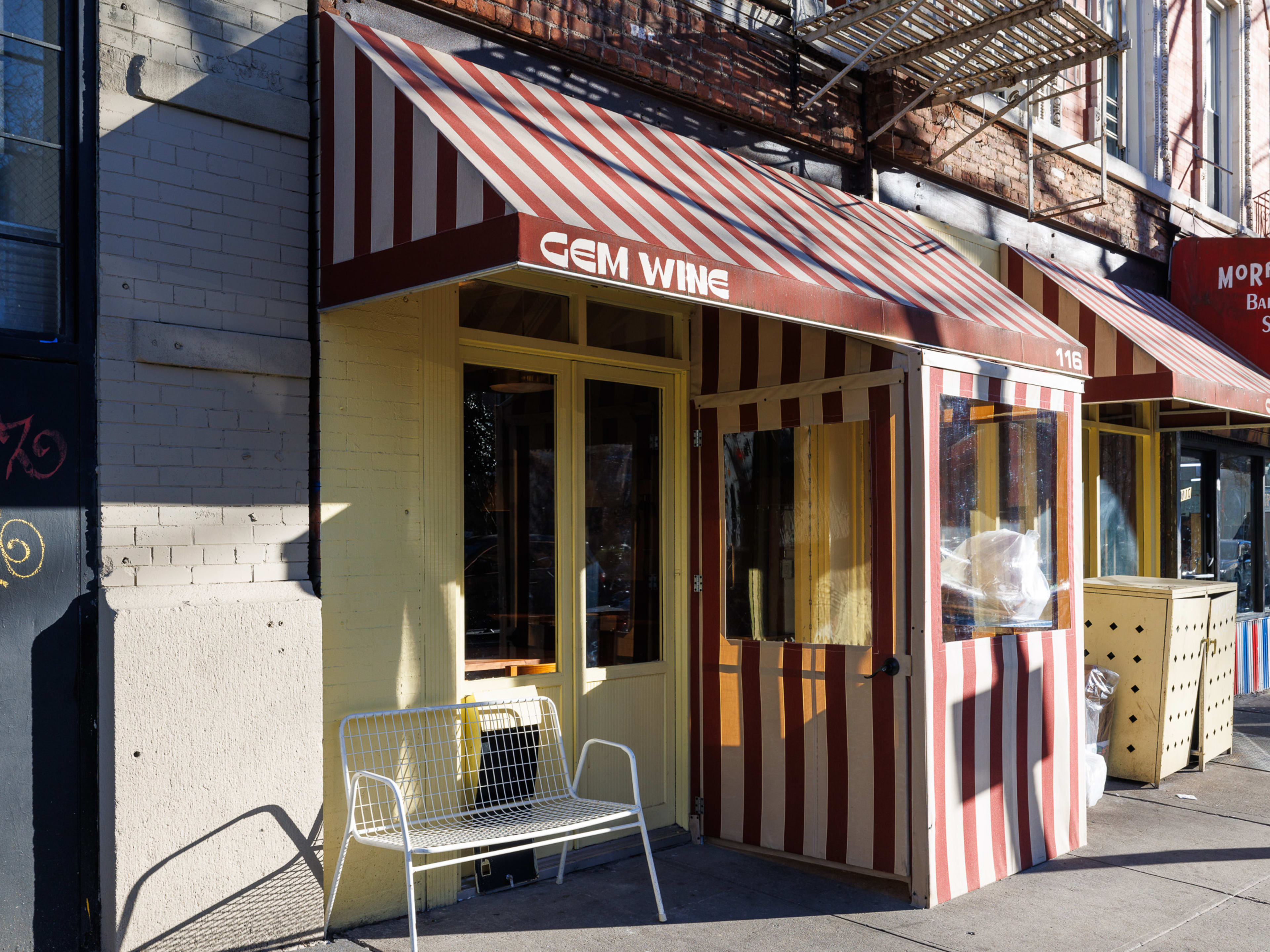 The exterior of Gem Wine. A restaurant door, with red and white striped awning