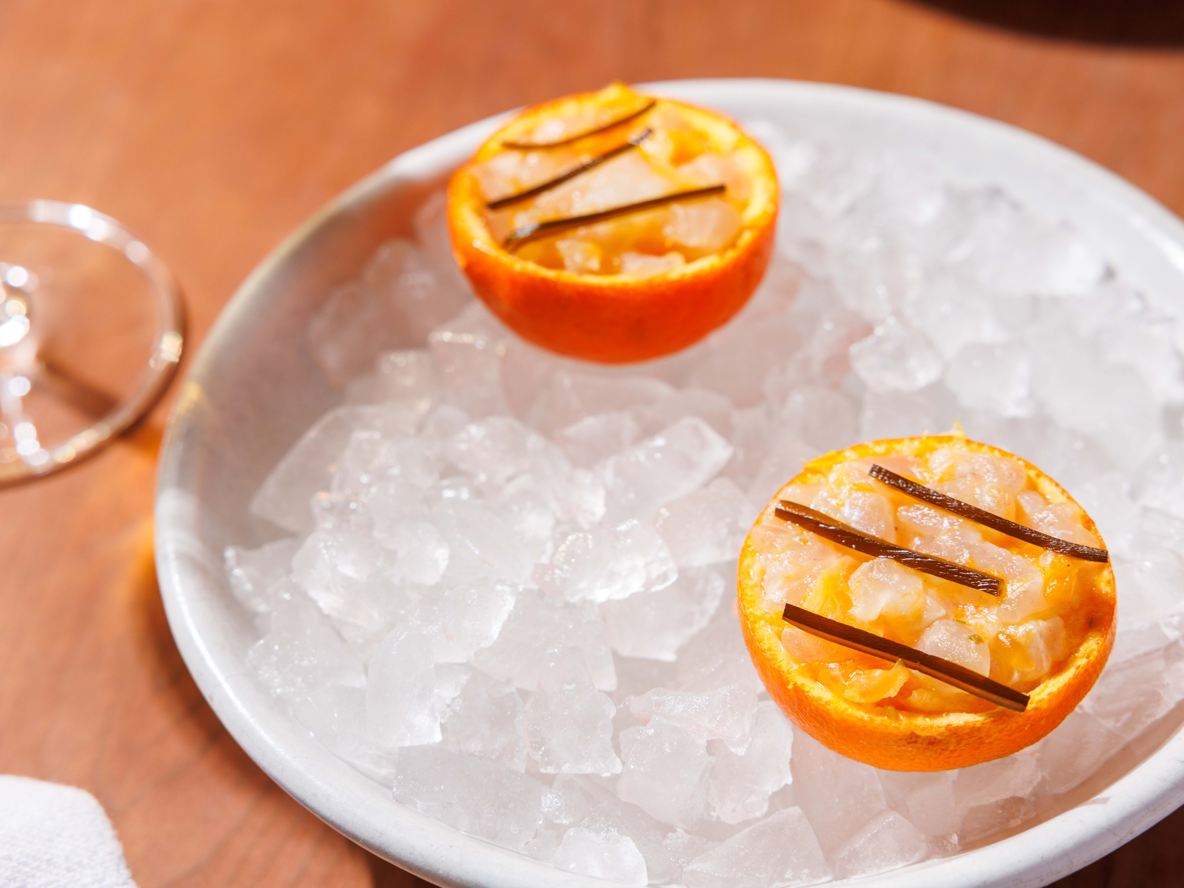 a fluke crudo served inside a satsuma orange peel over crushed ice