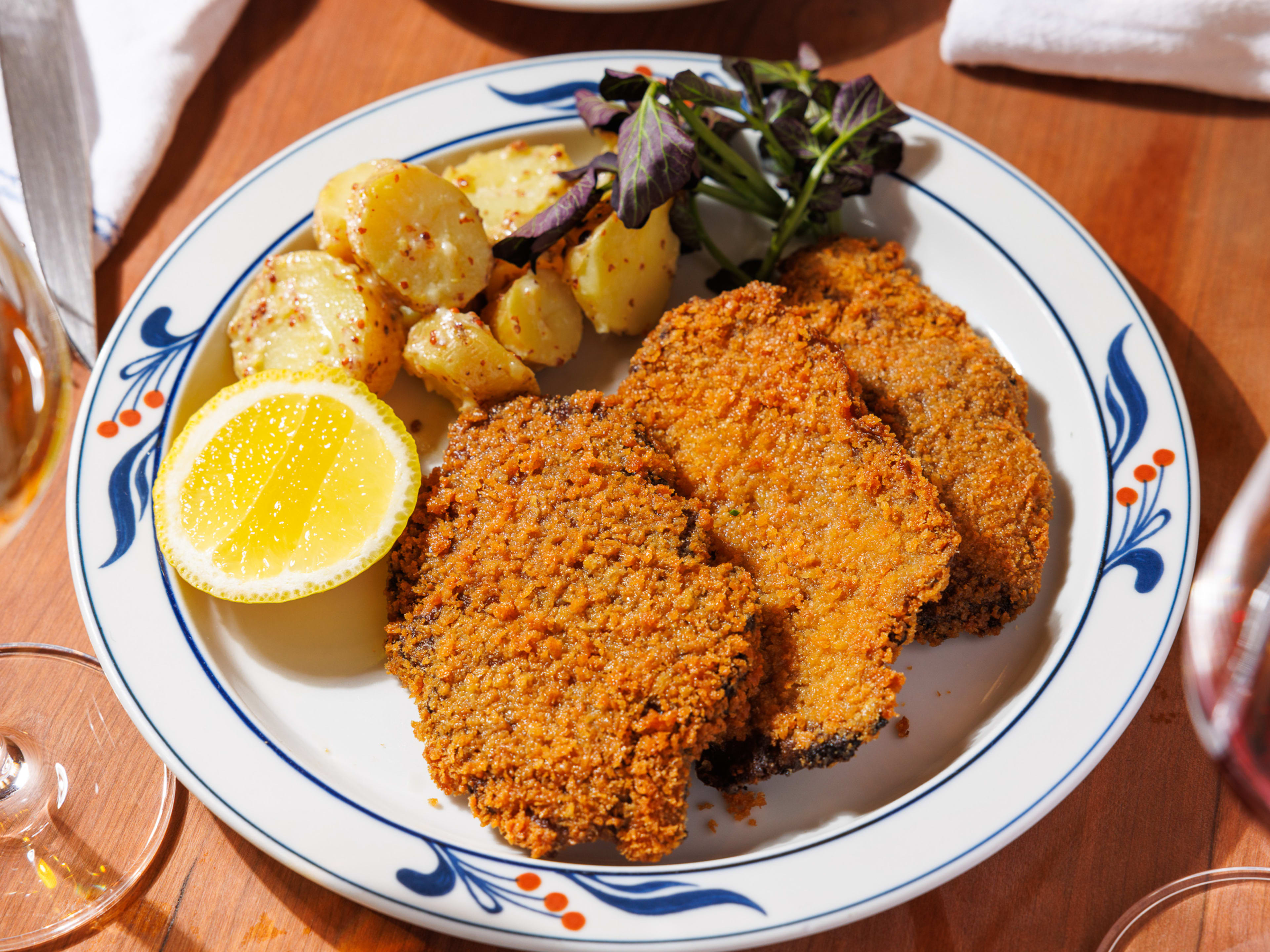 Three slabs of lions mane schnitzel, a lemon wedge, and German potato salad