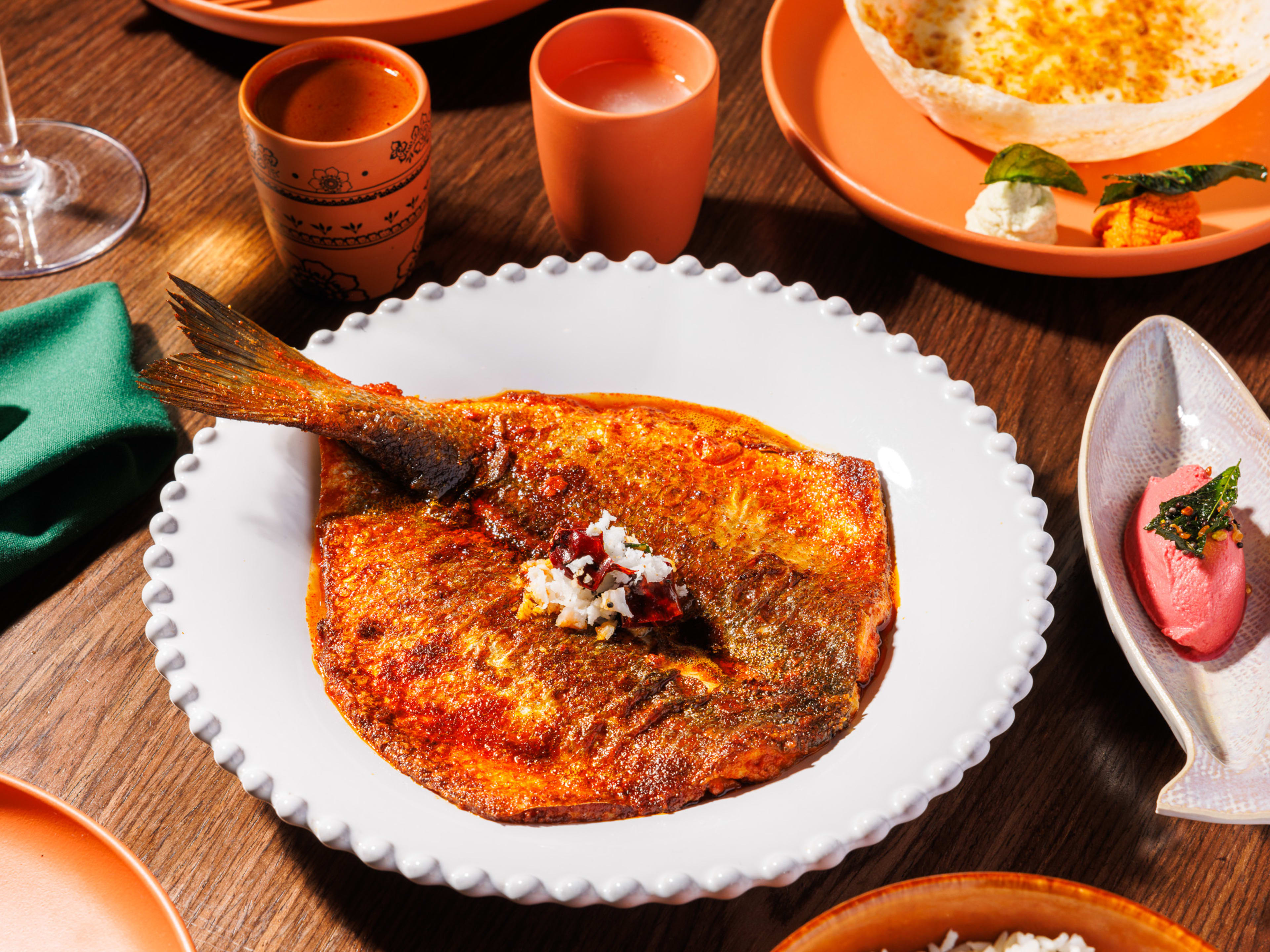 A crispy butterflied branzino sitting over a pool of brick-red curry.