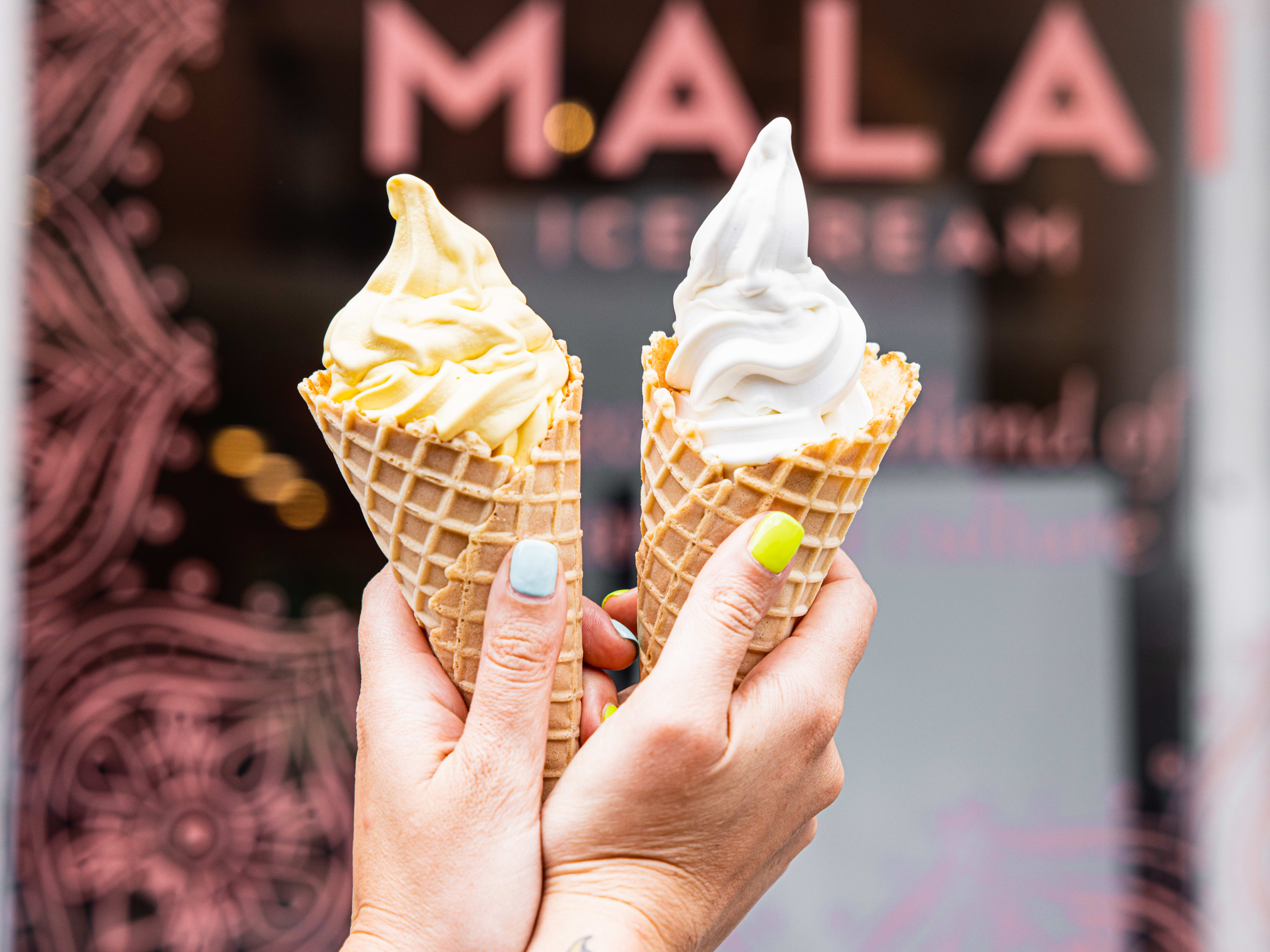 A cone of mango and a cone of coconut soft serve.