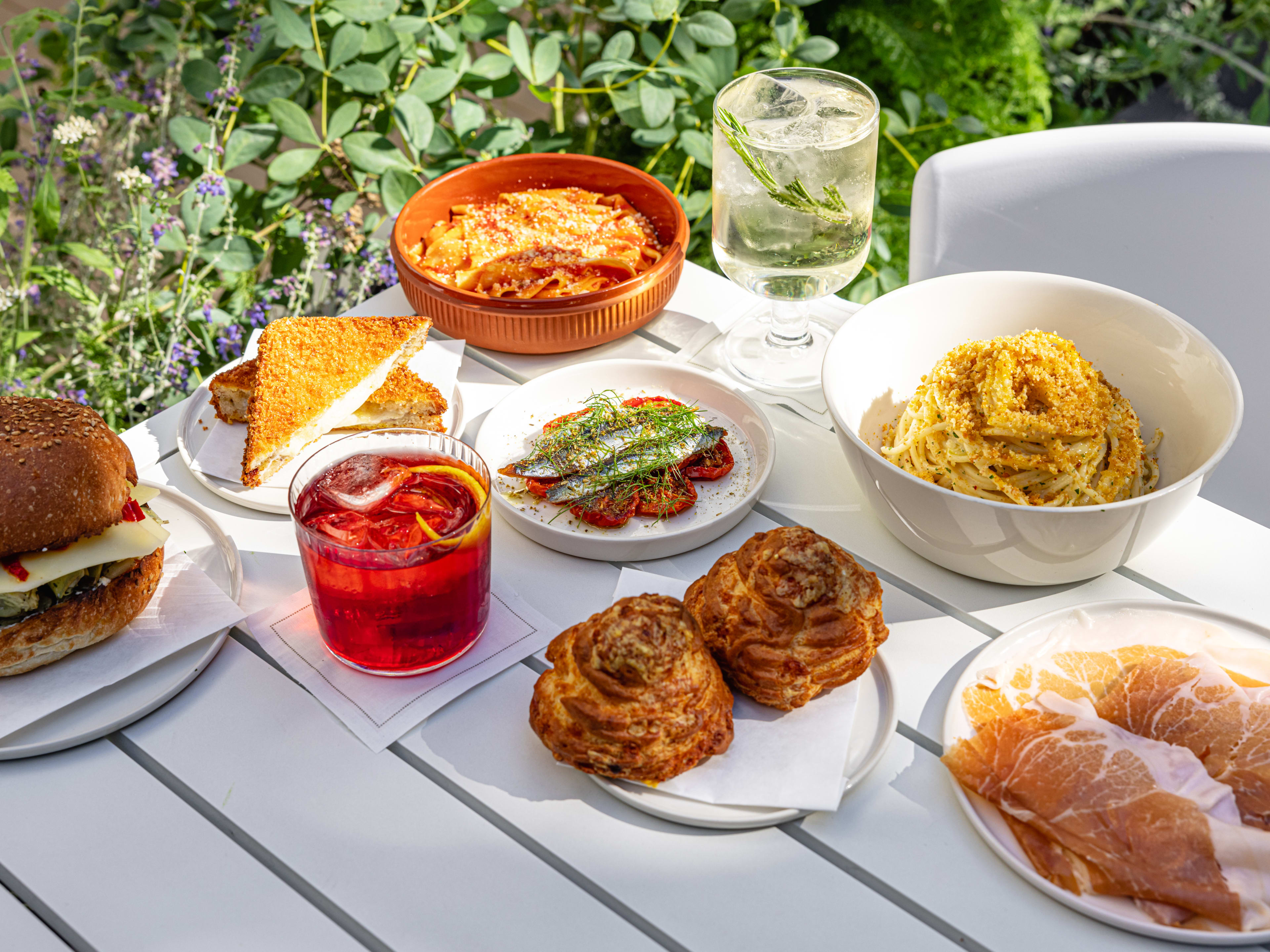 A spread of dishes from Misipasta on a white table outside.