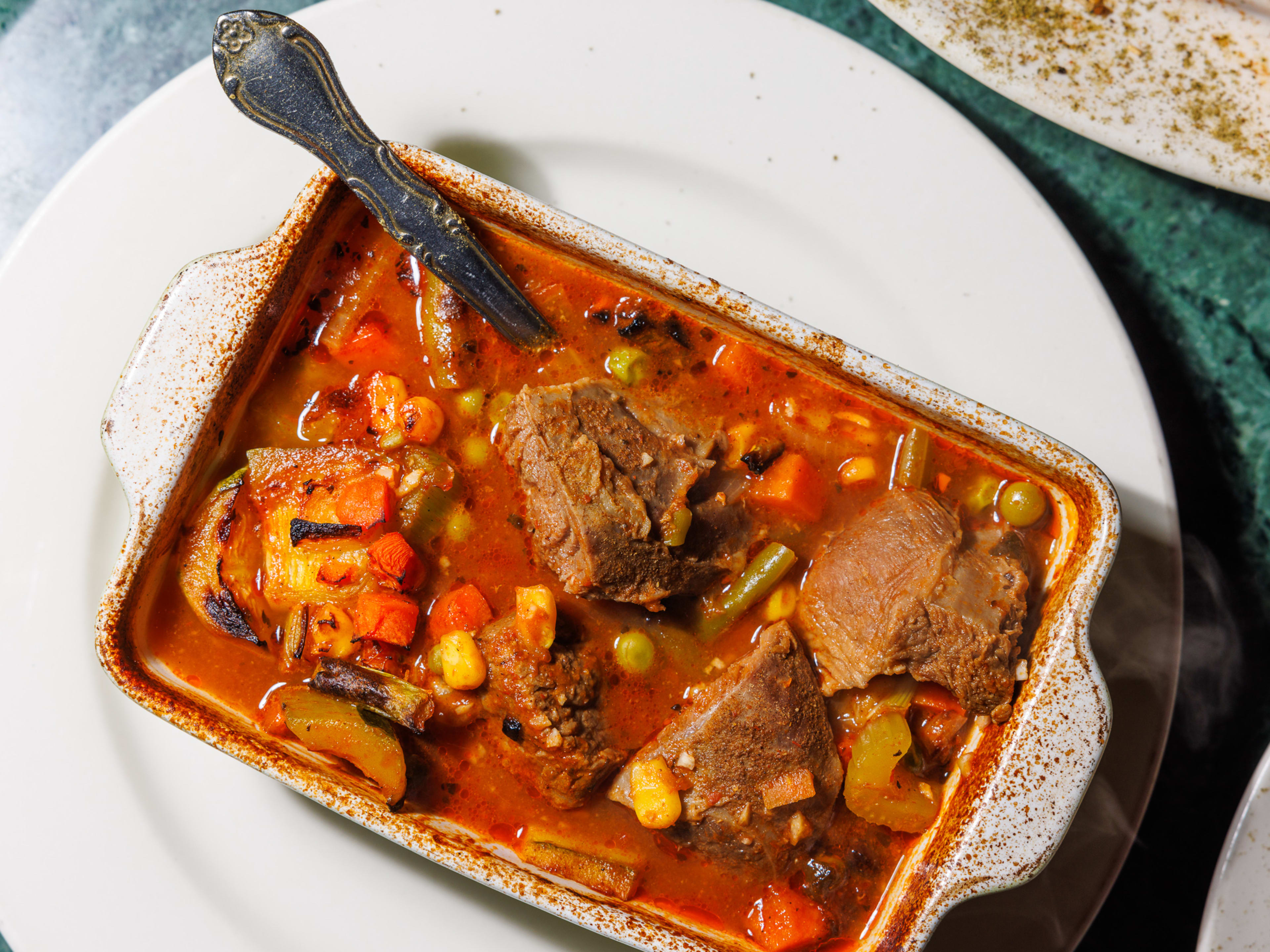 Lamb tagine in a white dish on a white plate.