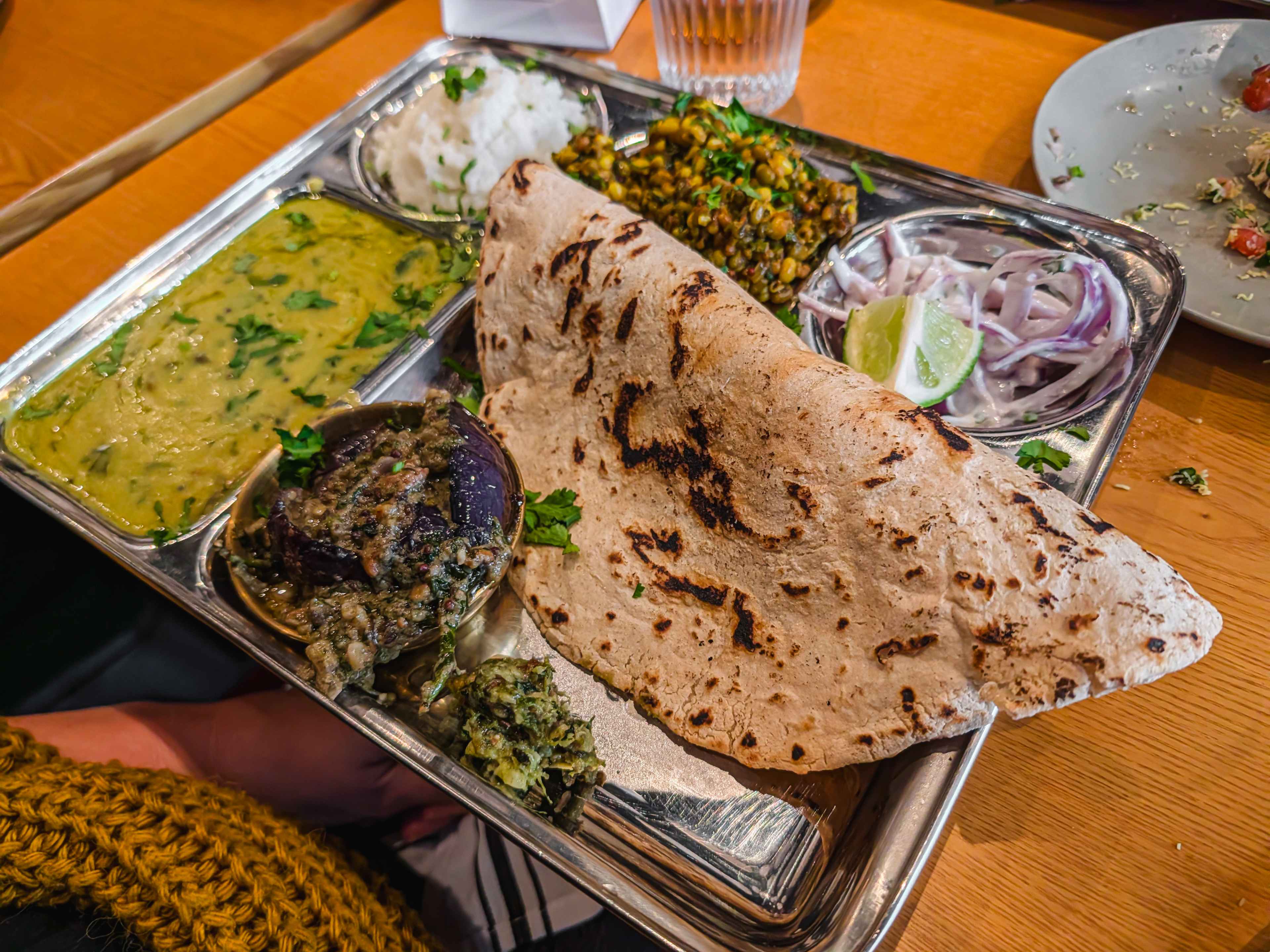 vegetarian thali with eggplant, mashed chickpea curry, sprouts and onions