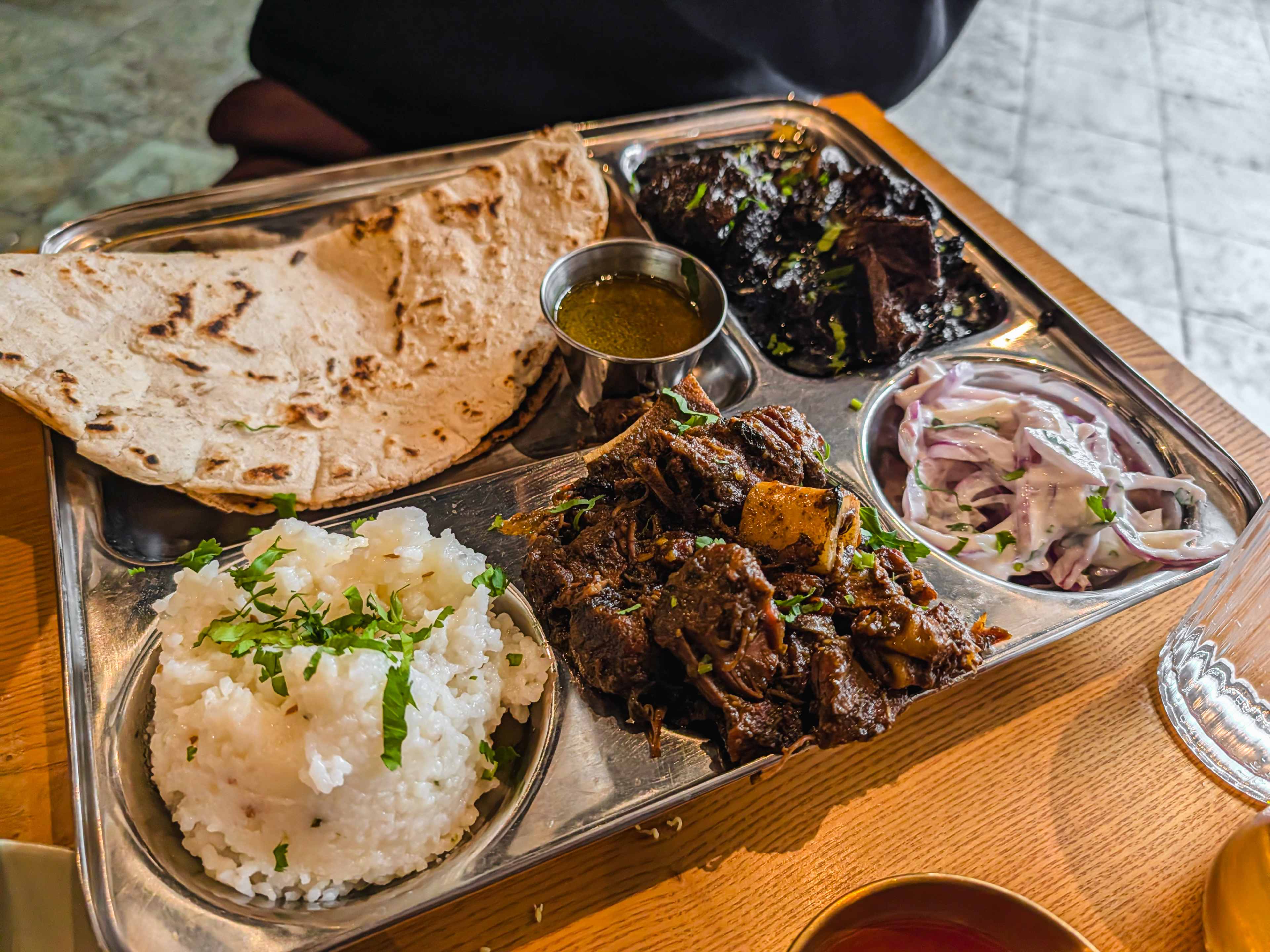 thali with rice, two kinds of goat mutton curry, onions and a flatbread