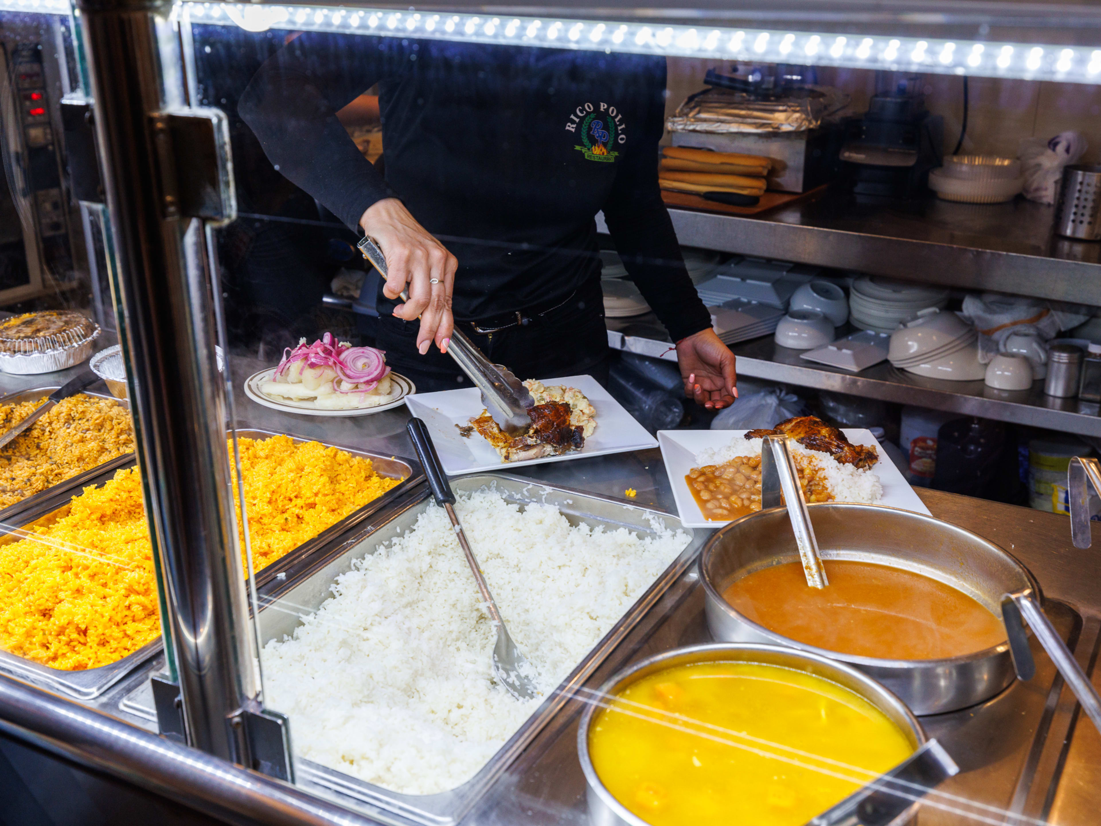 A counter with trays of rice, stew, and other foods.