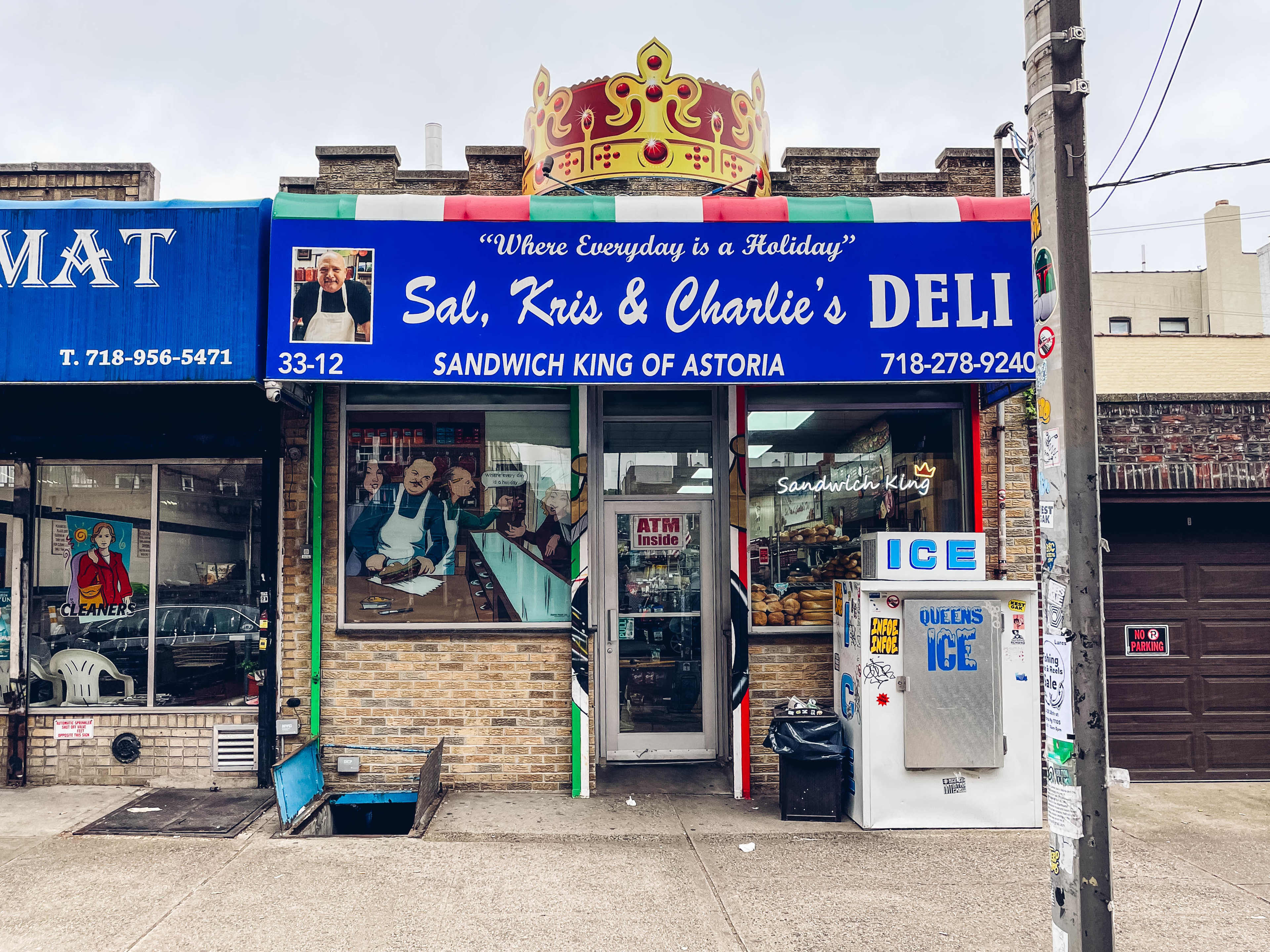 the outside of sal, kris, and charlie's deli in Astoria, which has a blue awaning and a large crown