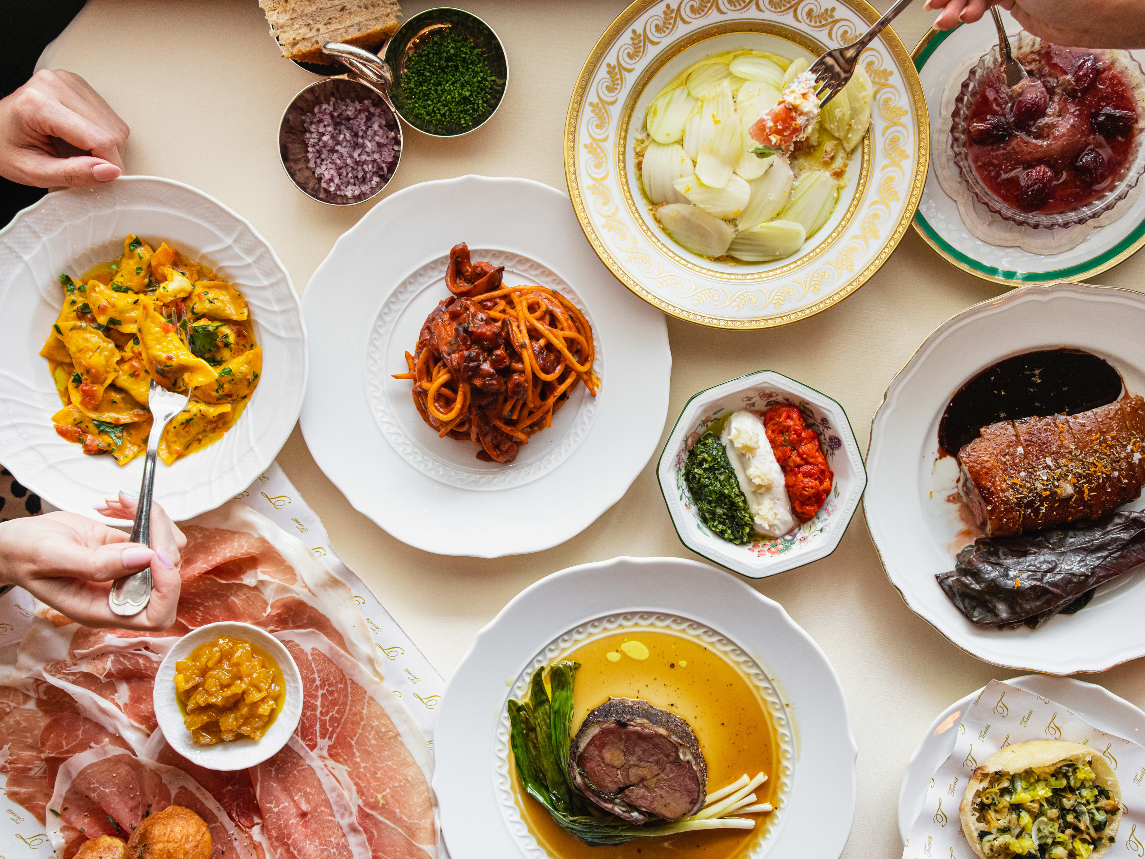 A big spread of Italian dishes, including duck, fennel salad, pasta, and prosciutto.