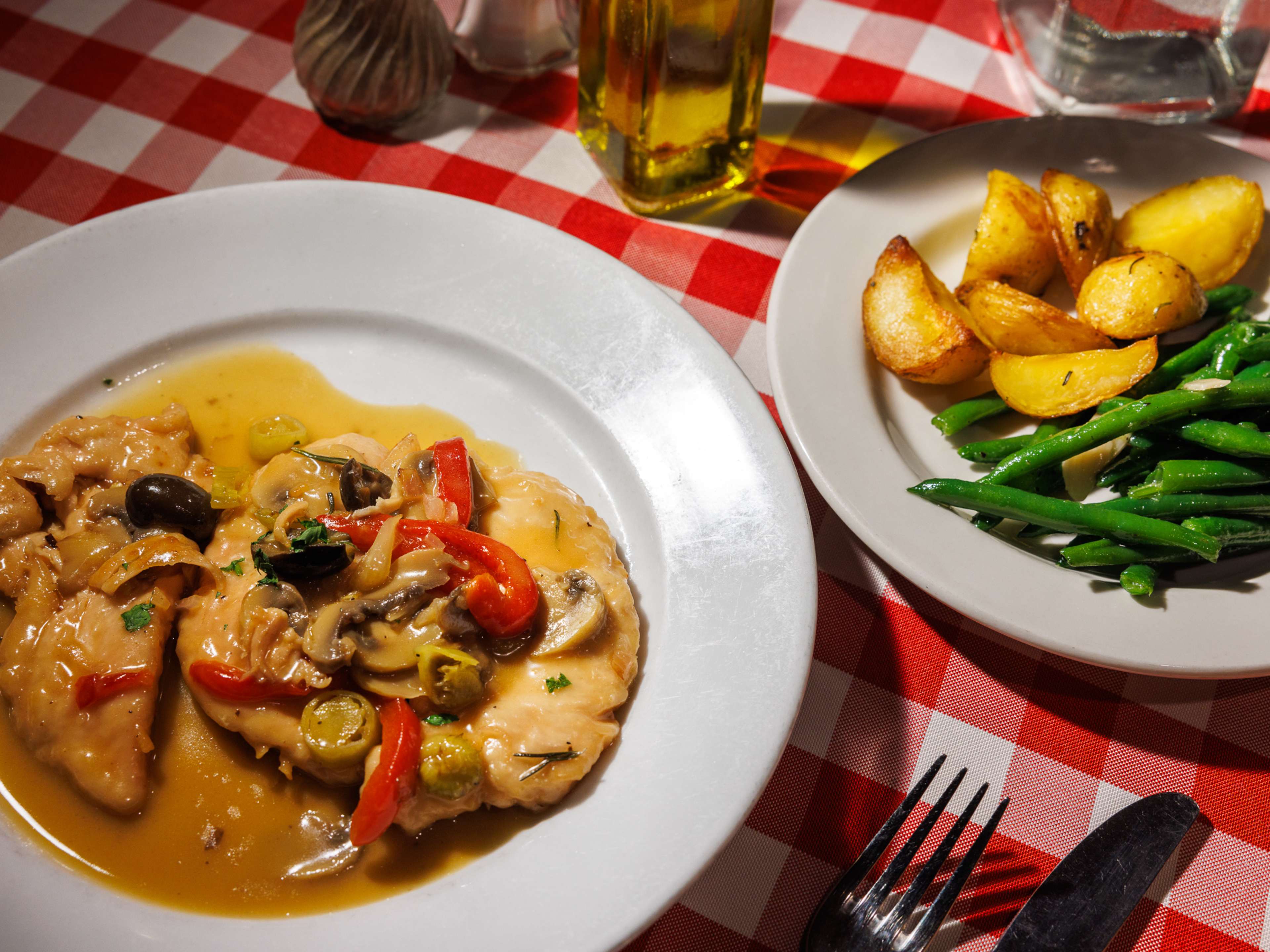 A plate with chicken and a plate with potatoes and green beans.