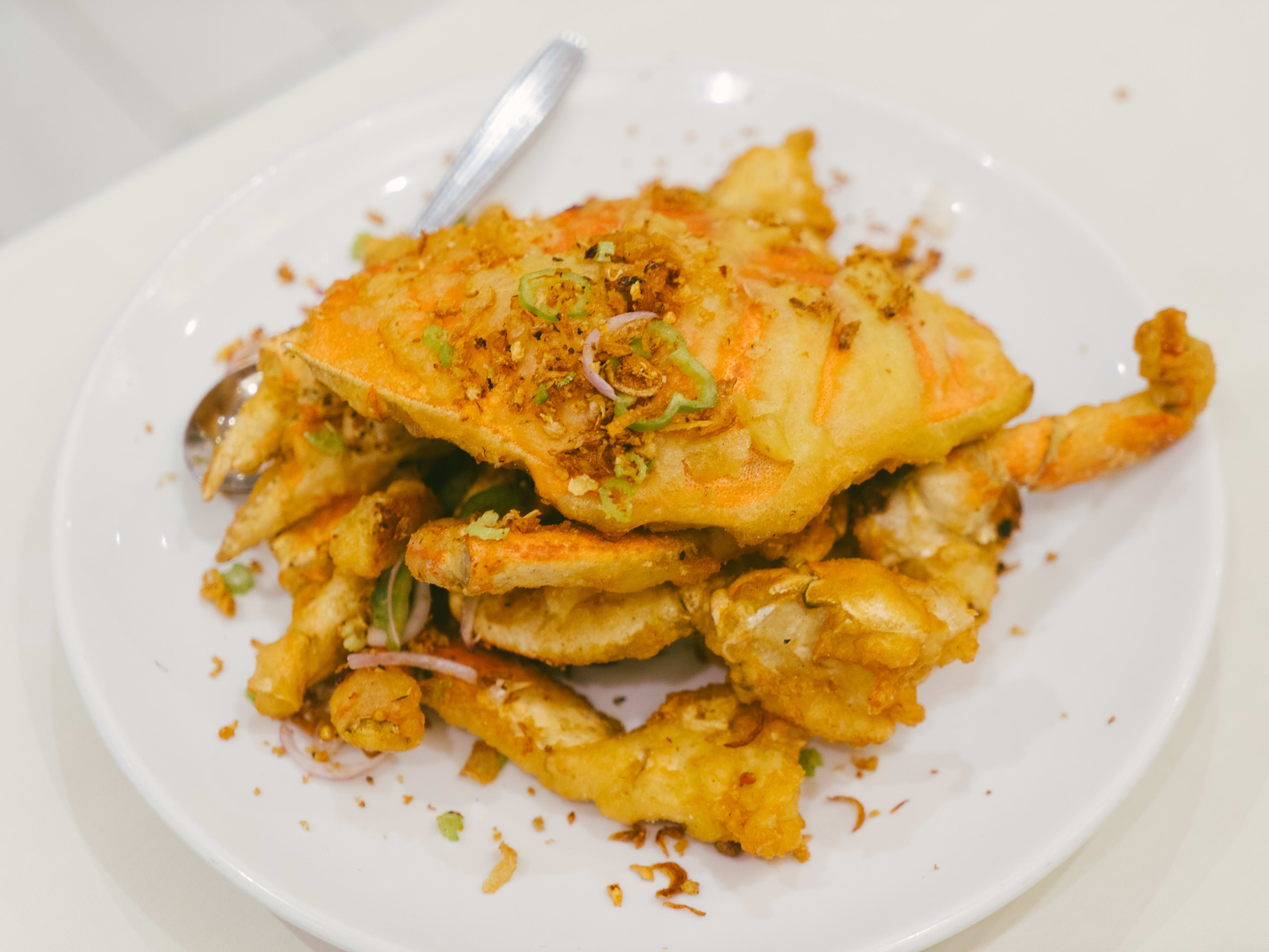 A whole fried crab broken into pieces on a plate.