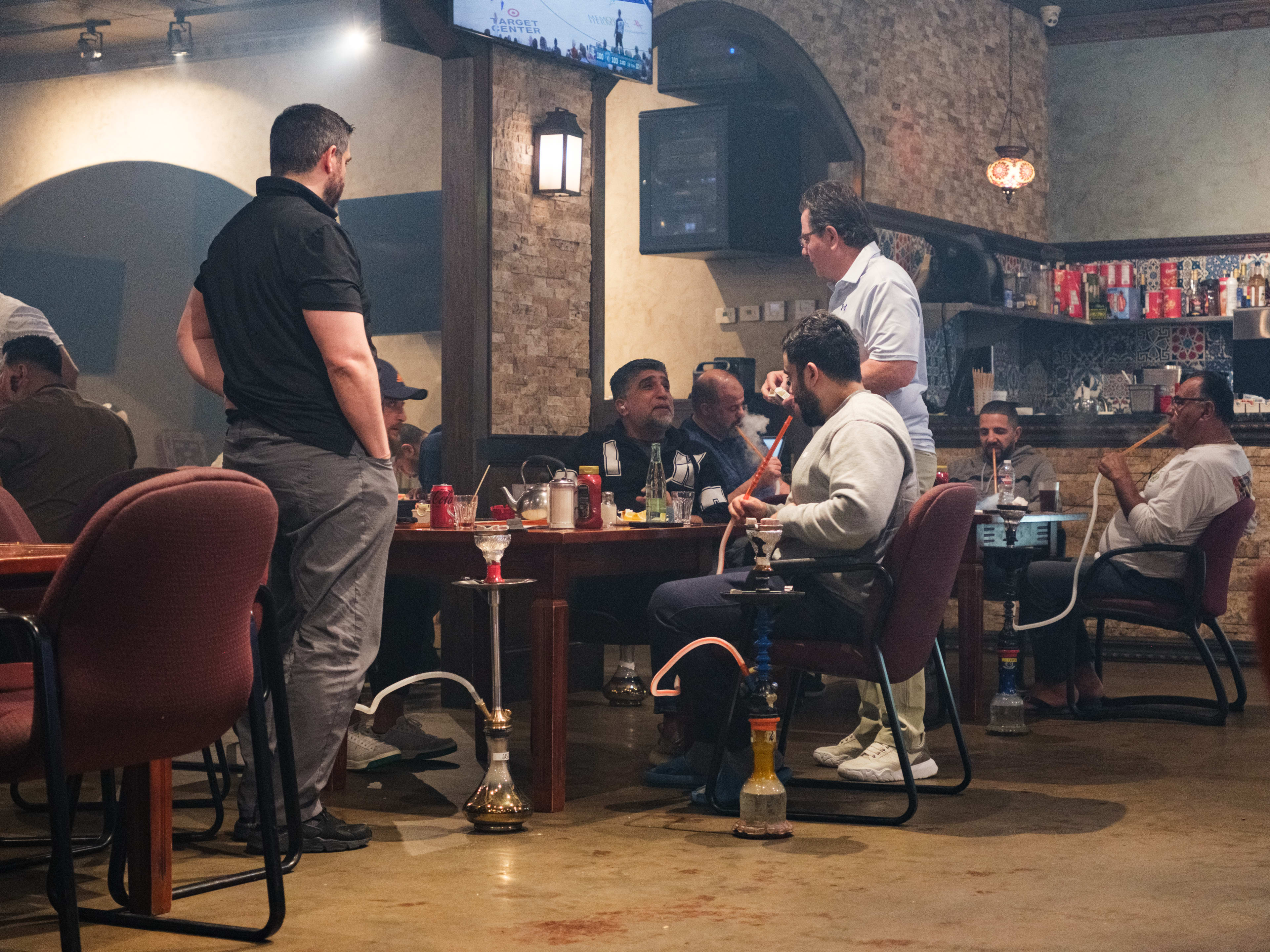 People sitting and standing around a table smoking hookah.