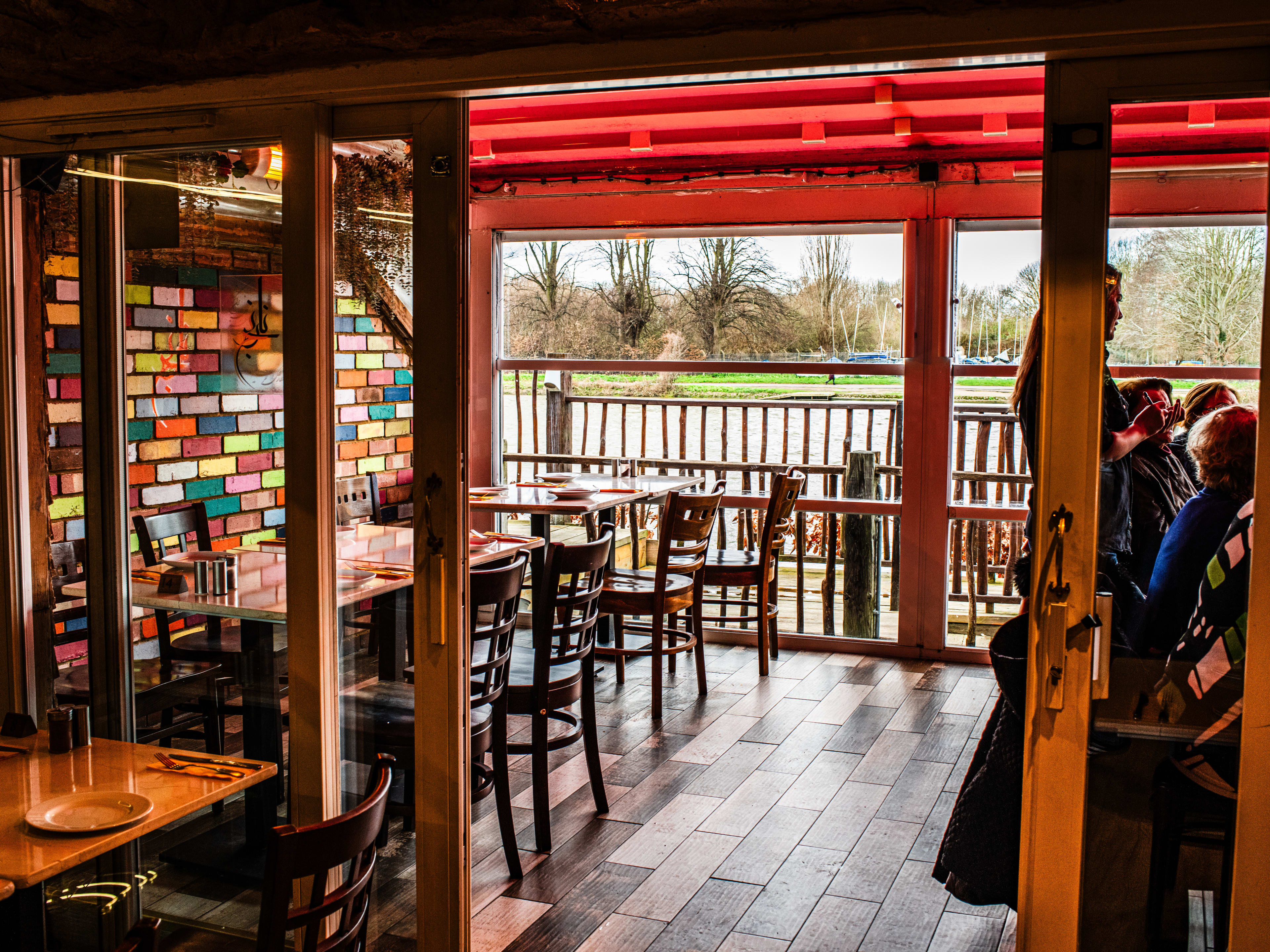 Sliding doors open onto the patio at Narenj Persian Restaurant. There are colorful bricks on the wall, and a red awning.