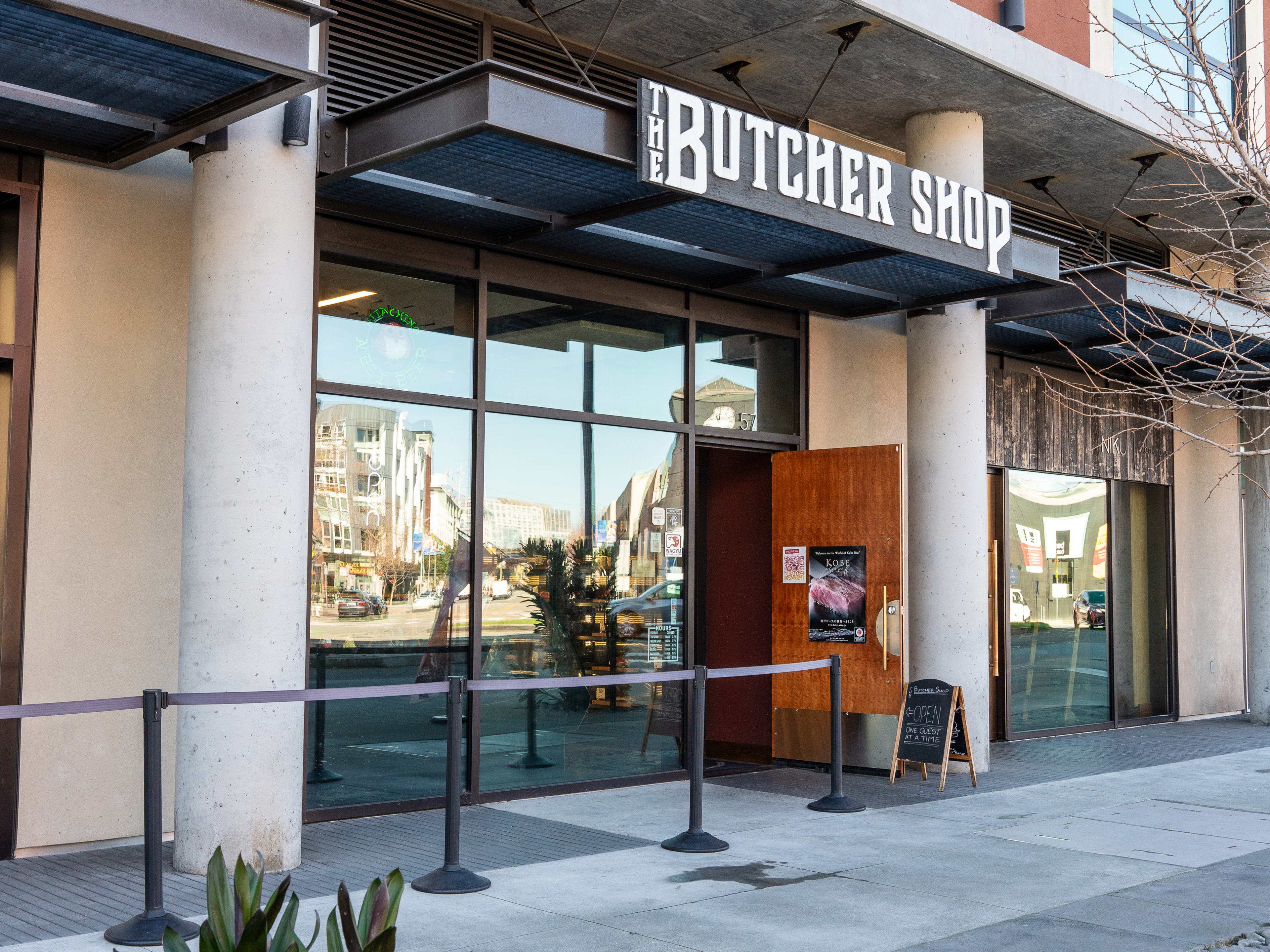 exterior of butcher shop with door propped open and stanchions ready for line