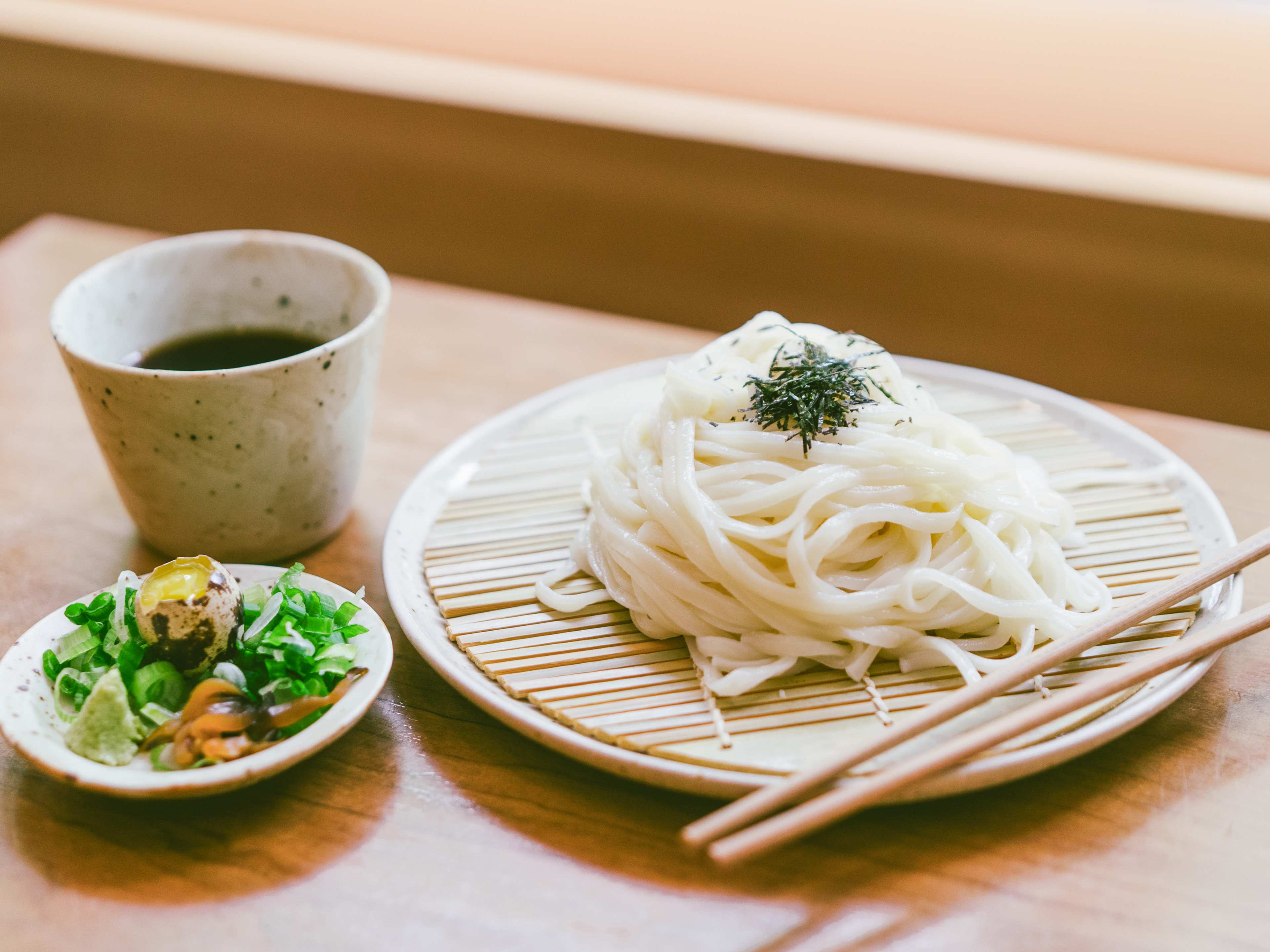 udon with a broth next to them and a quail egg with pickles