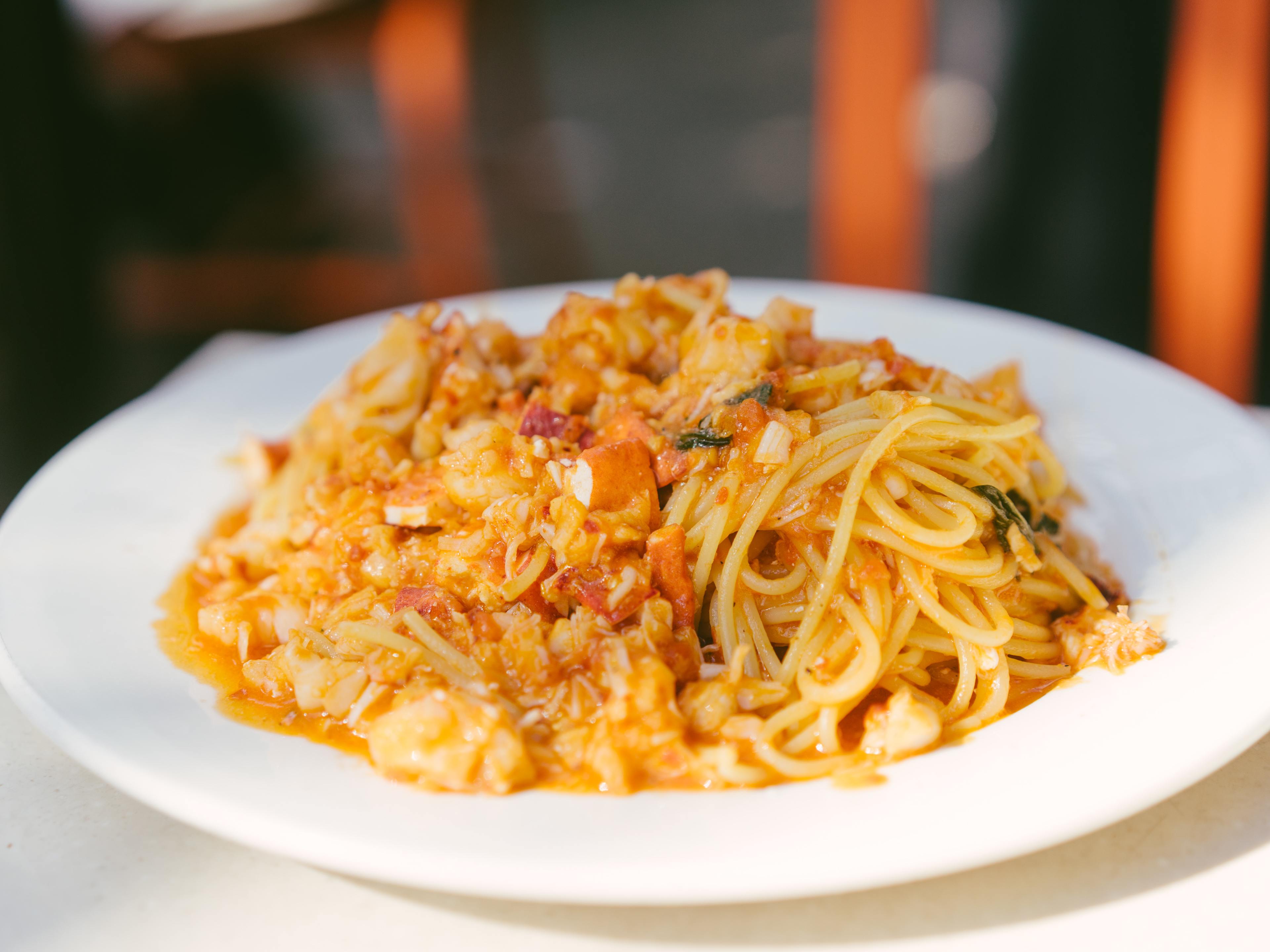 A plate of pasta topped with chunks of lobster in a sauce