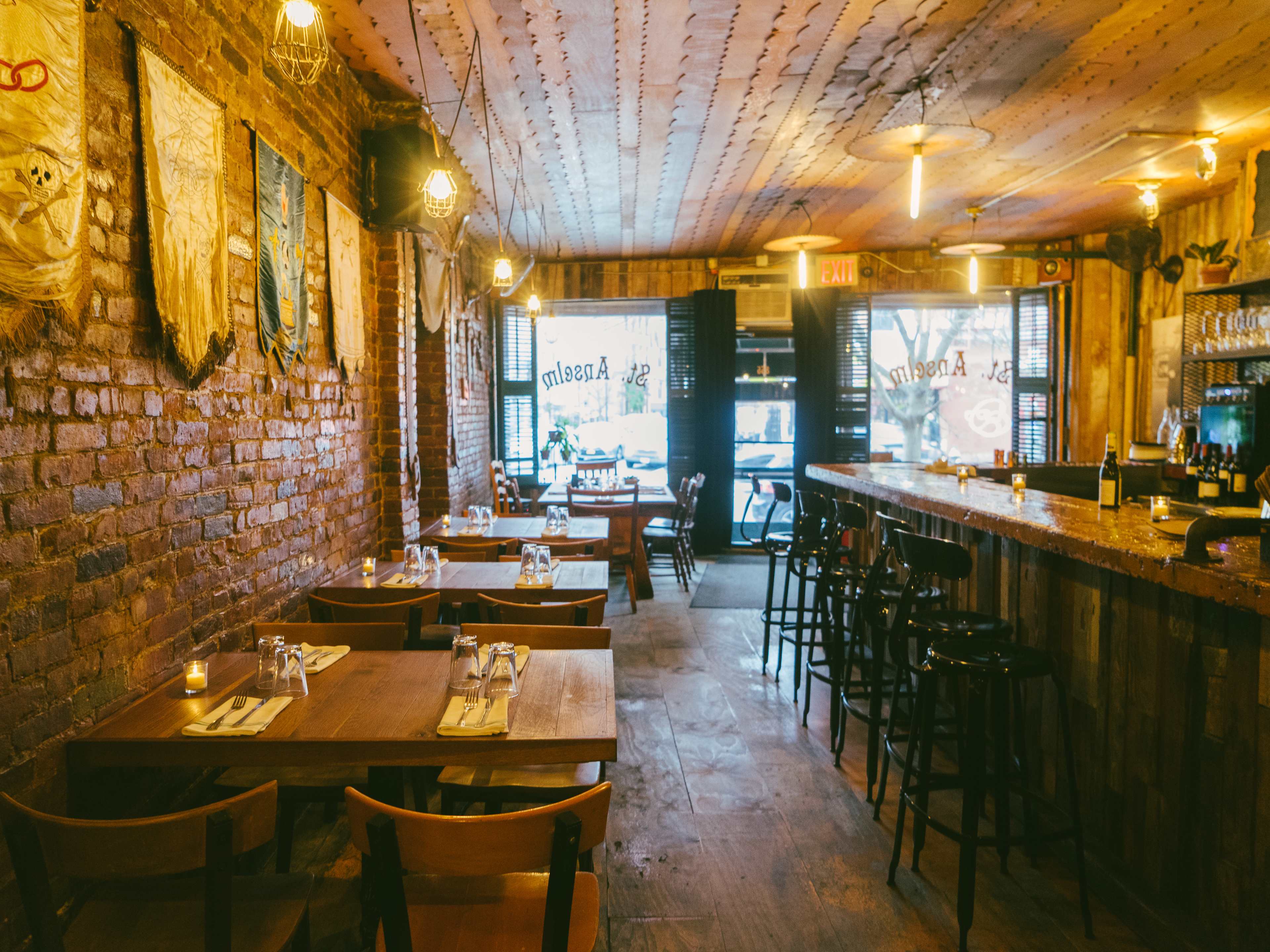 A small dining room with brick walls and plain wooden tables.