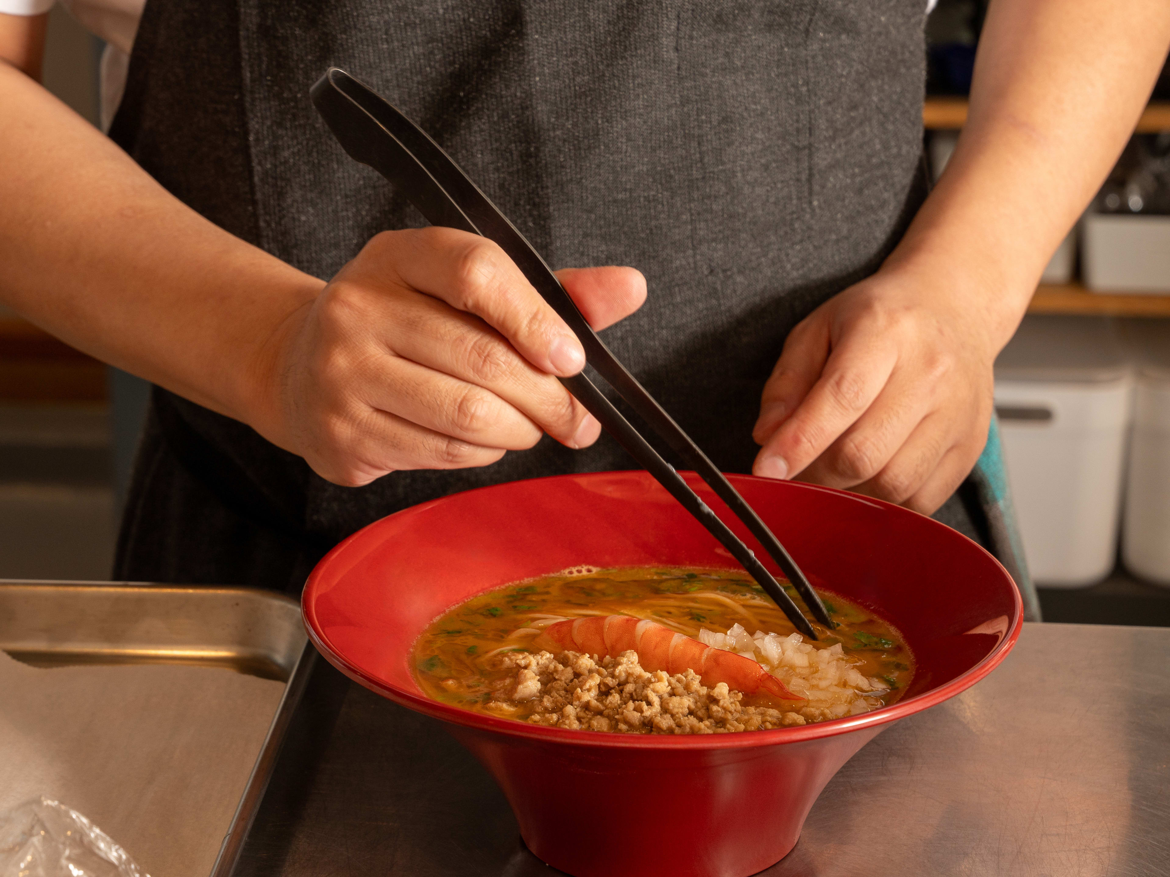 Staff putting the finishing touches on a bowl of ramen at Noodle In A Haystack