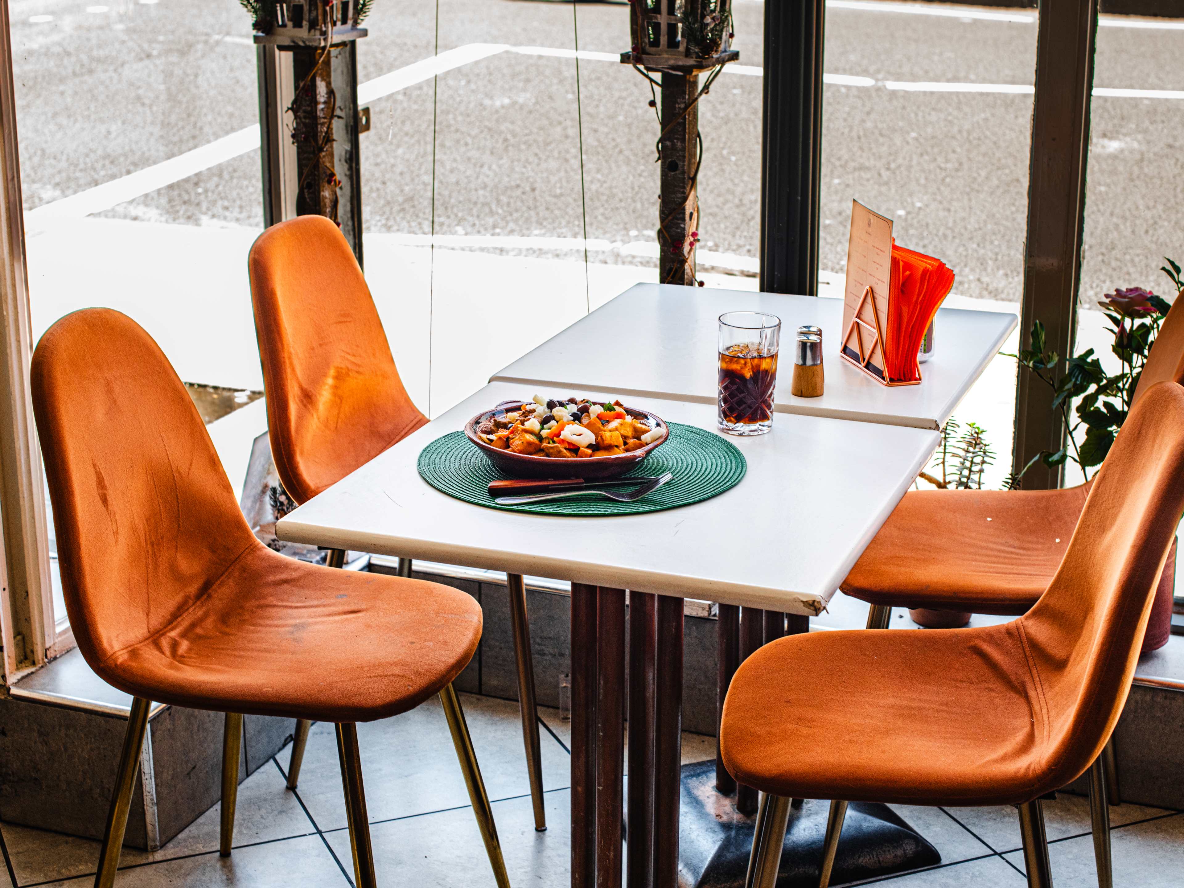 The porco à alentejana from O Cantinho De Portugal on a window table surrounded by rust colored chairs.