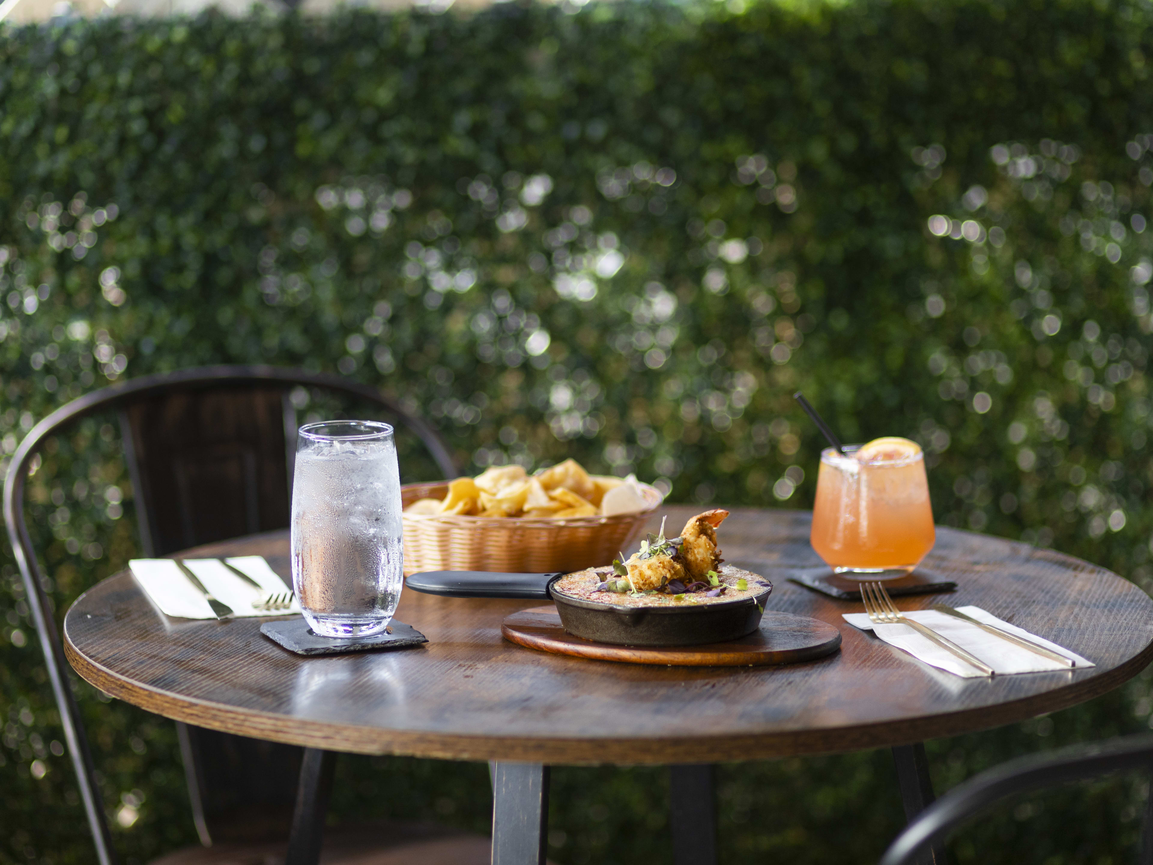 Spread of food and cocktails on dark wooden table at Oasis