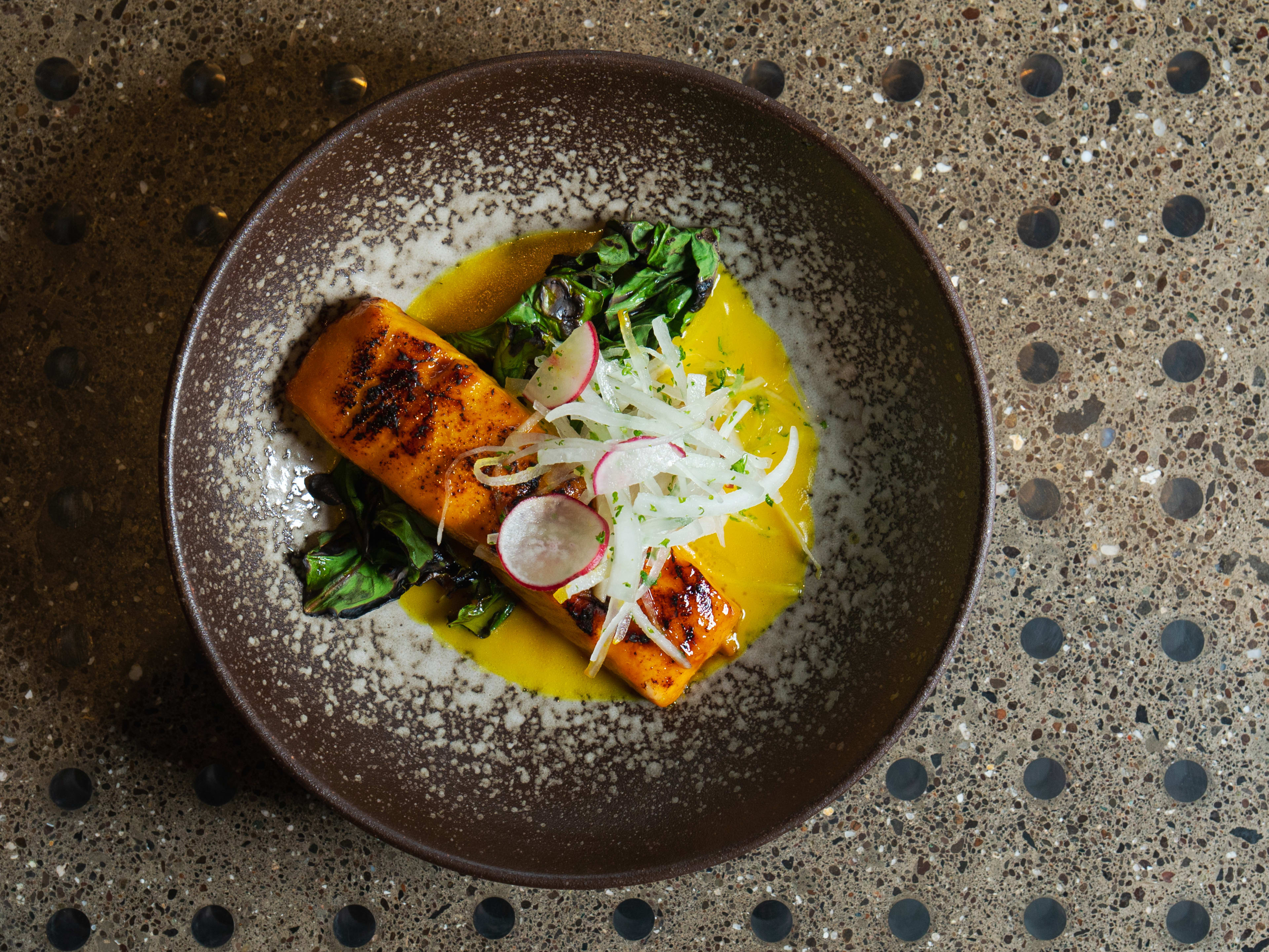 48-hour aged Atlantic salmon dish topped with raw vegetables at Ode