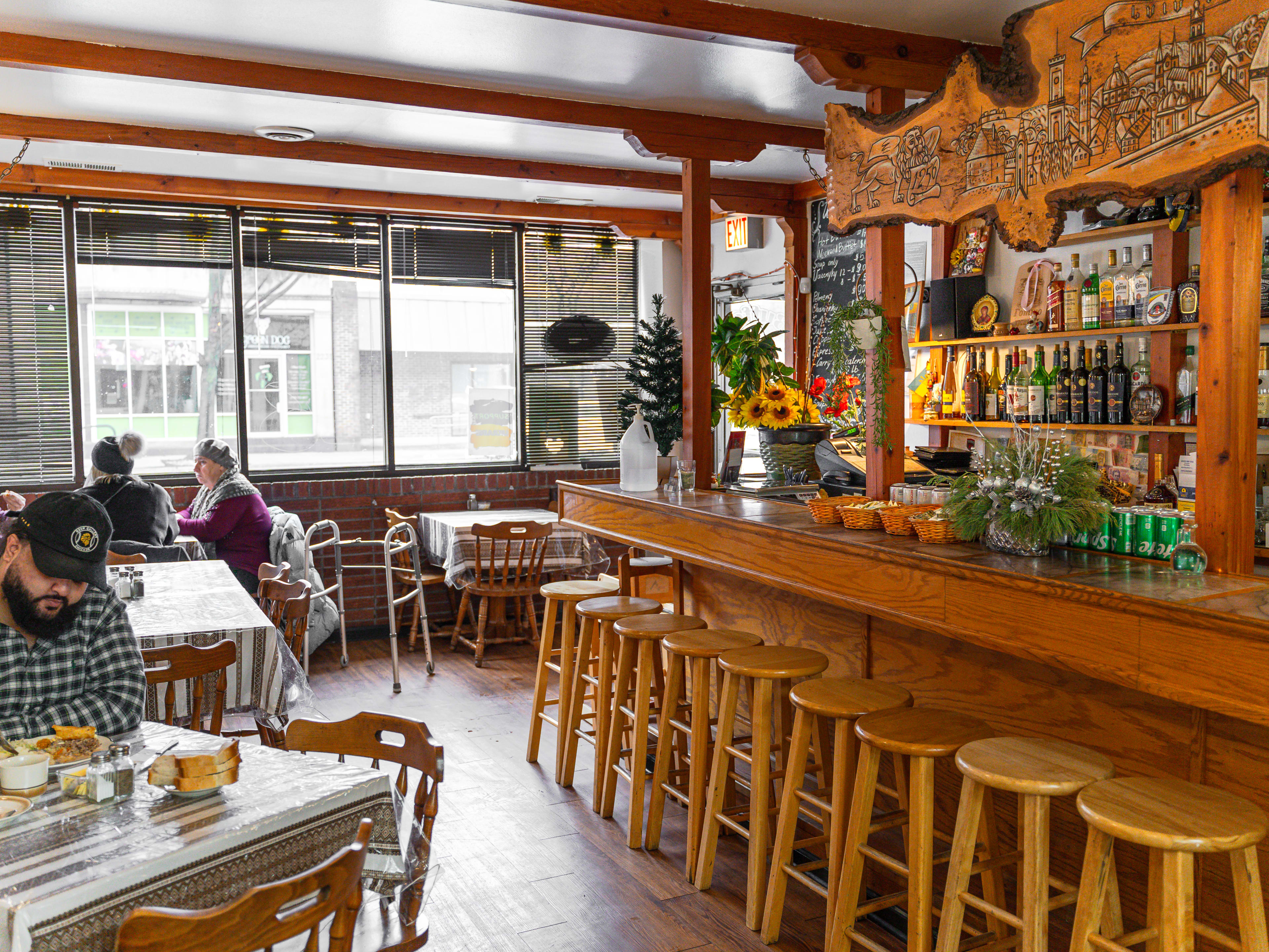 A tiny wooden restaurant with a small bar and a few tables with people eating.