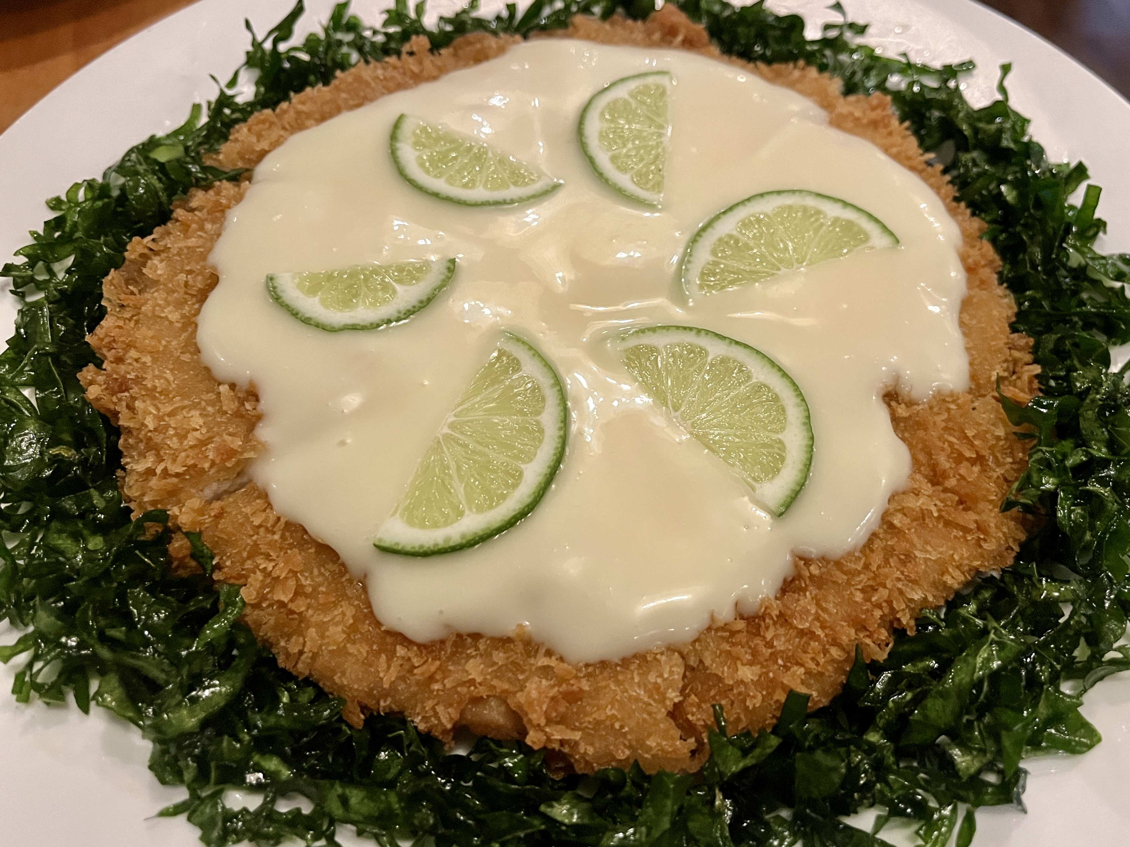 Fried chicken patty covered with a glaze and limes.