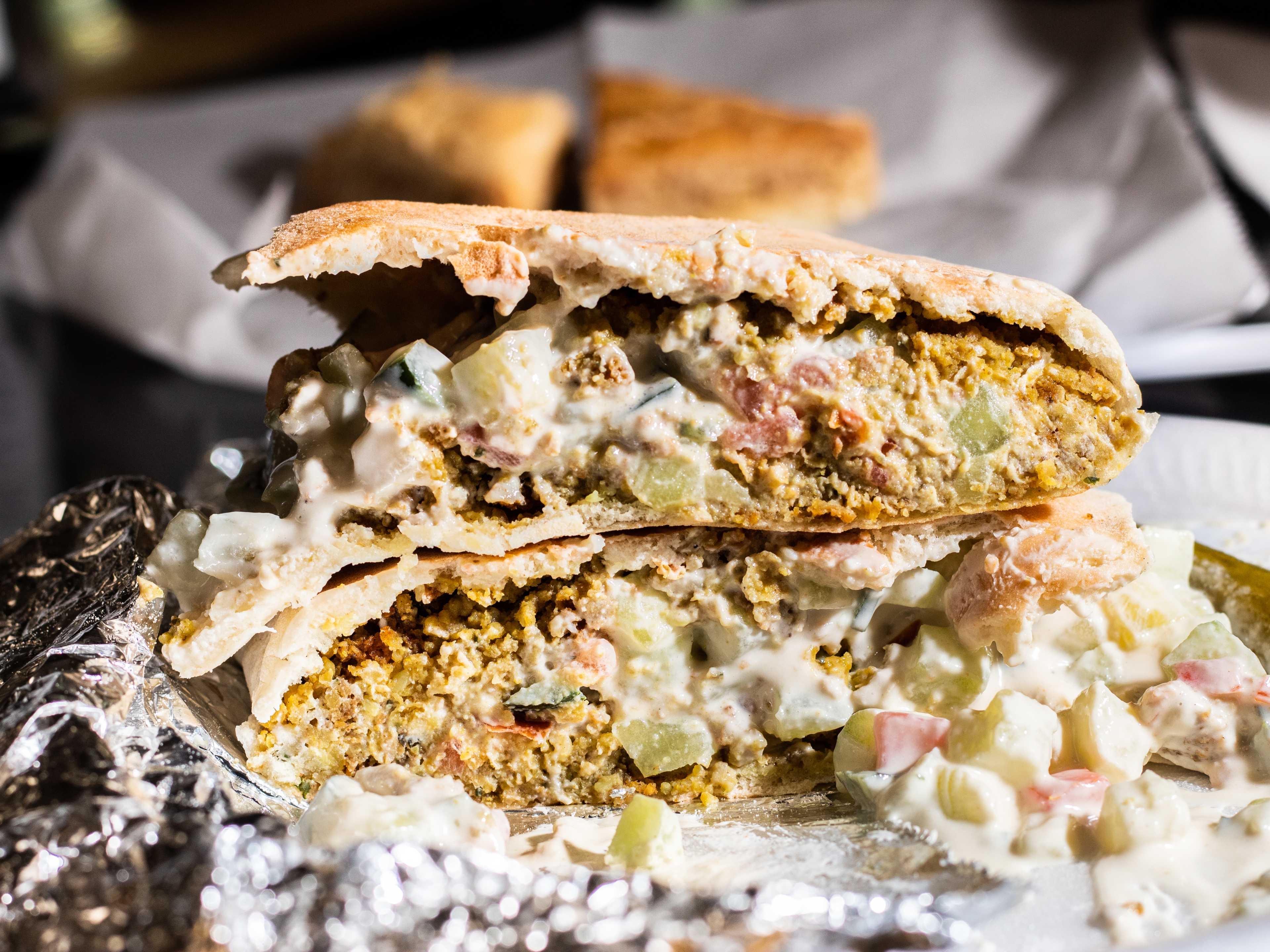 cross section of falafel pita with cucumber yogurt sauce spilling out