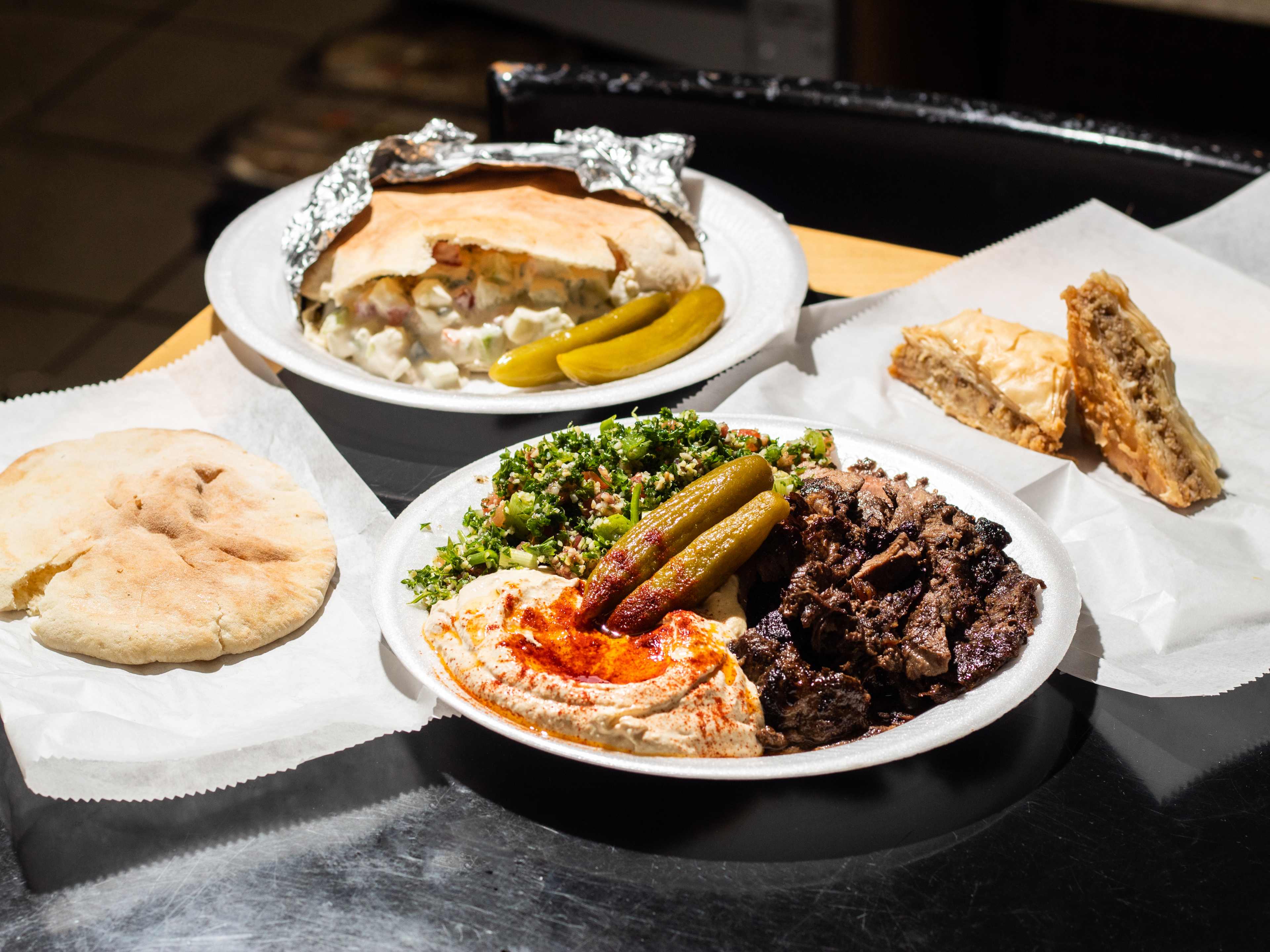 spread of dishes like falafel sandwich, shawarma plate, pita, and baklava