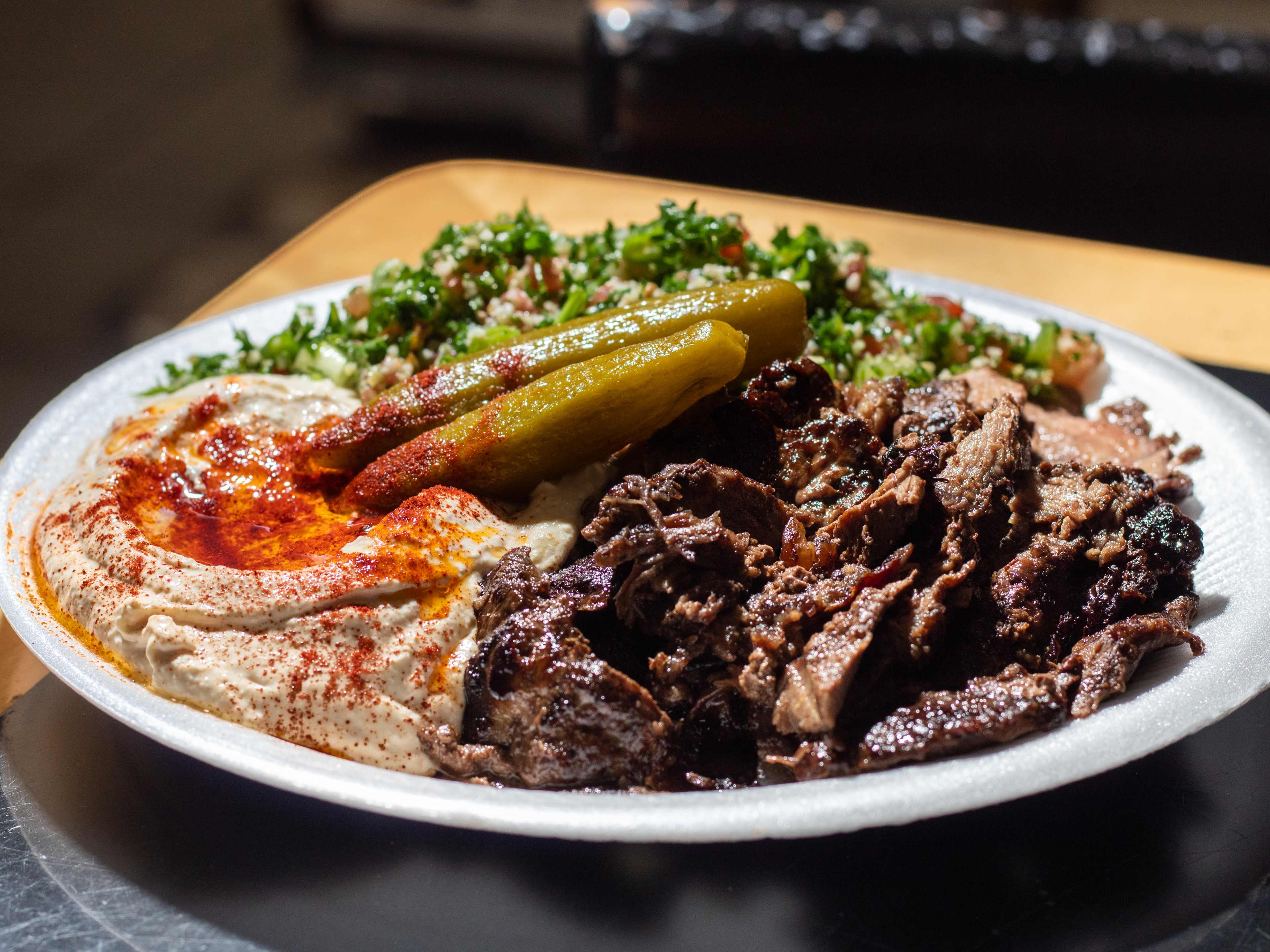 meat shawarma plate with silky, paprika-dusted hummus, pickles, and salad