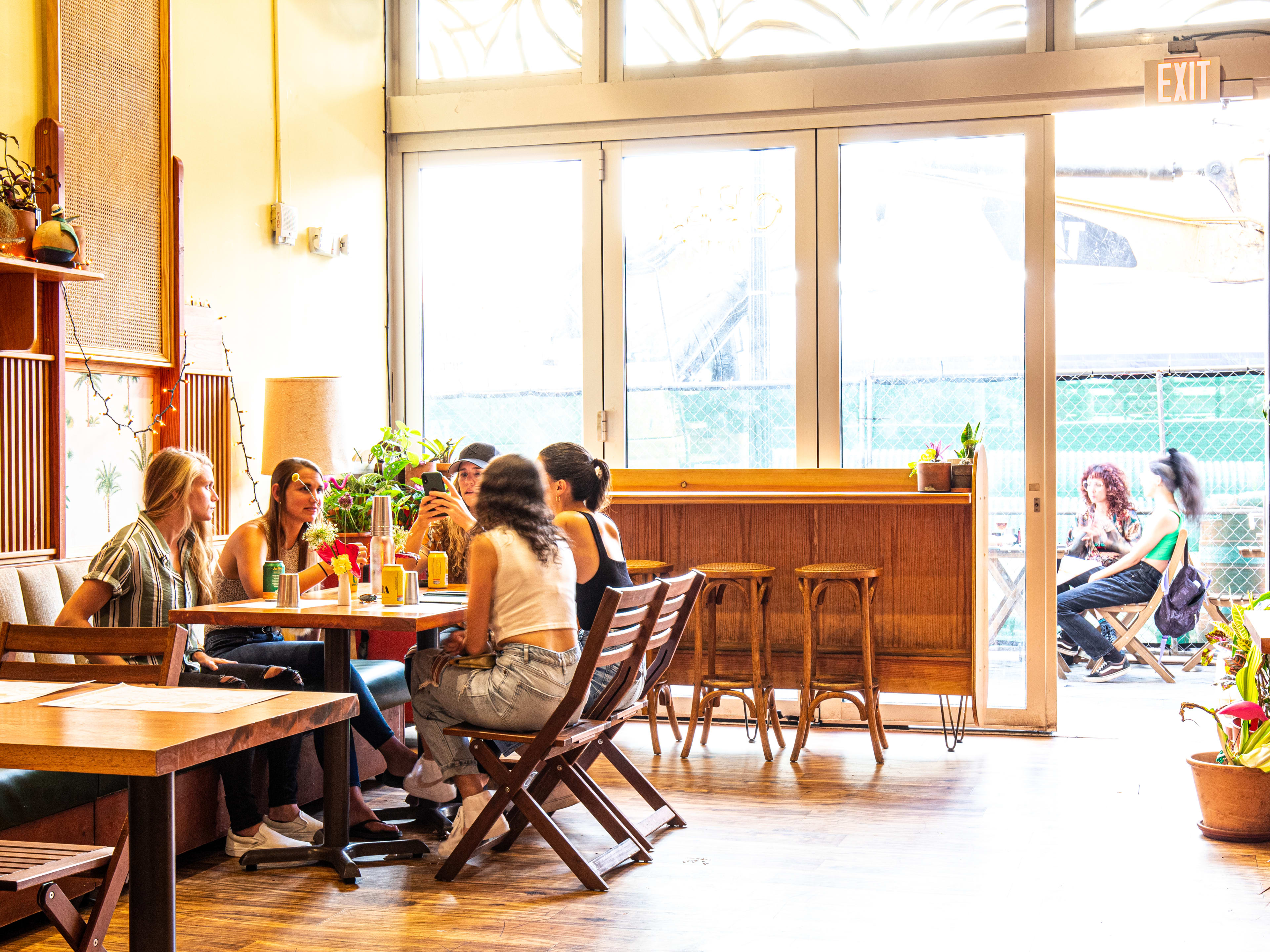 interior of sun-lit restaurant with booth seating and wooden chairs.