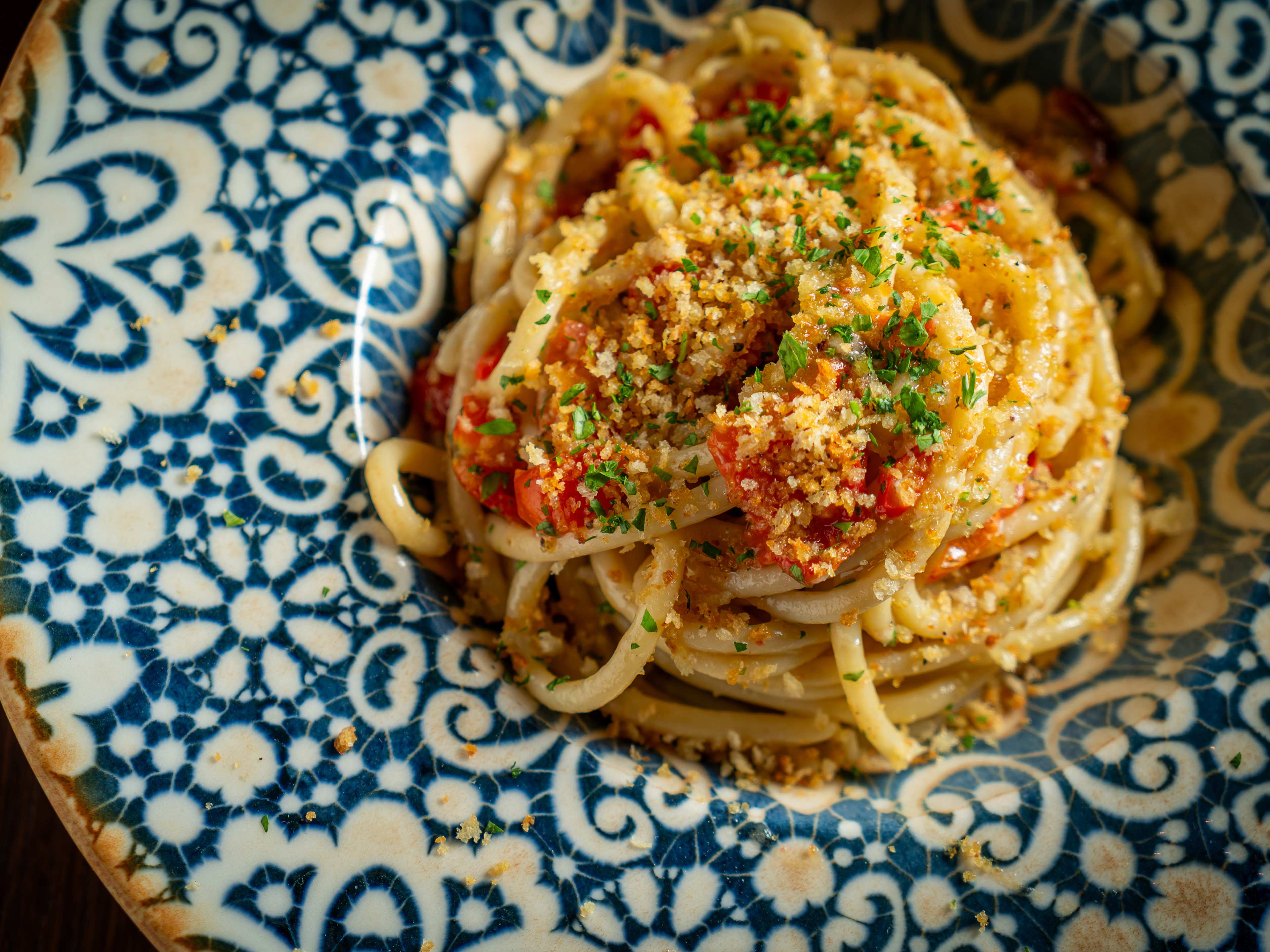 a bowl of pasta with breadcrumbs and tomato