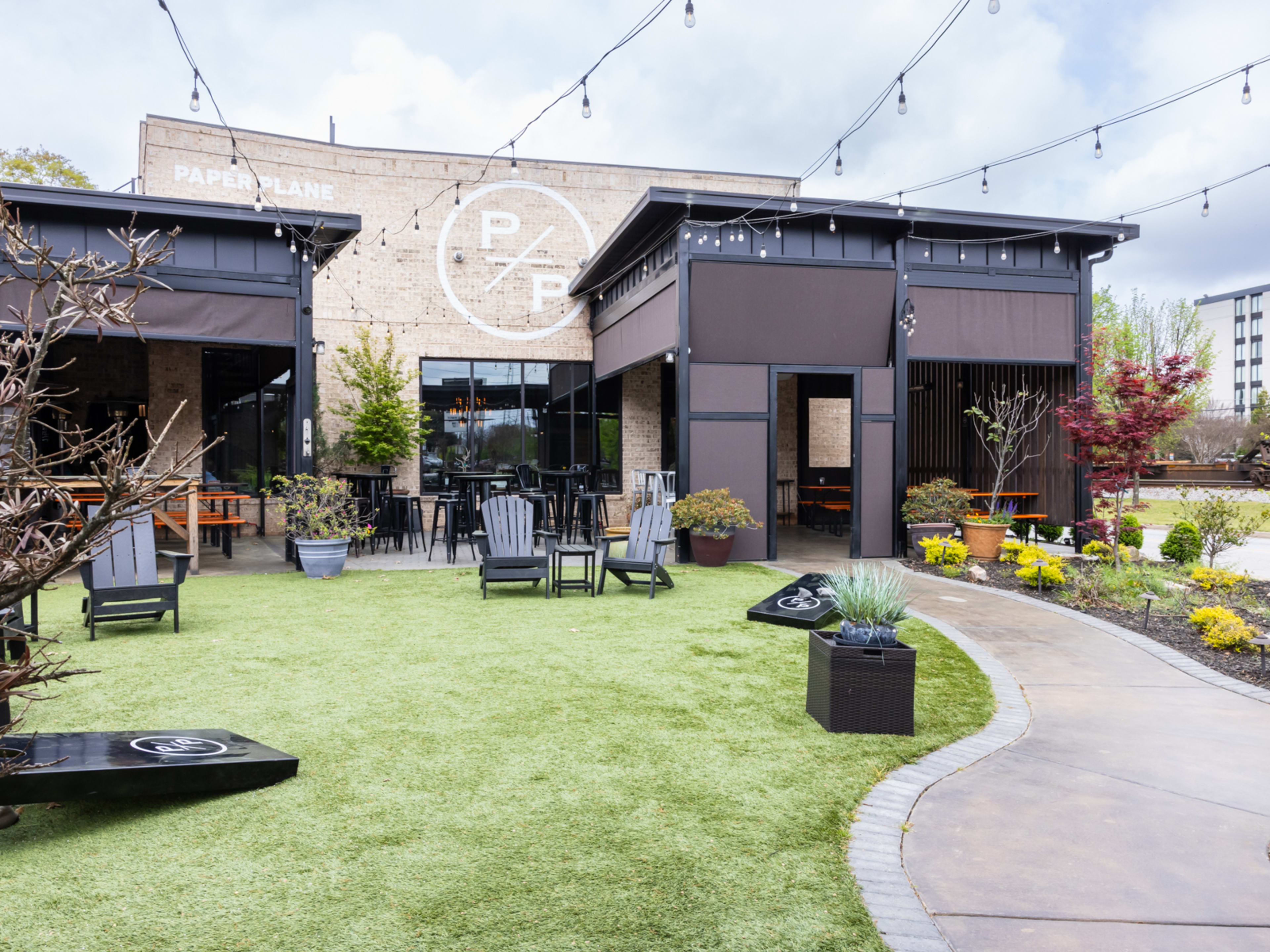 exterior of restaurant with lawn, patio seating, and cornhole