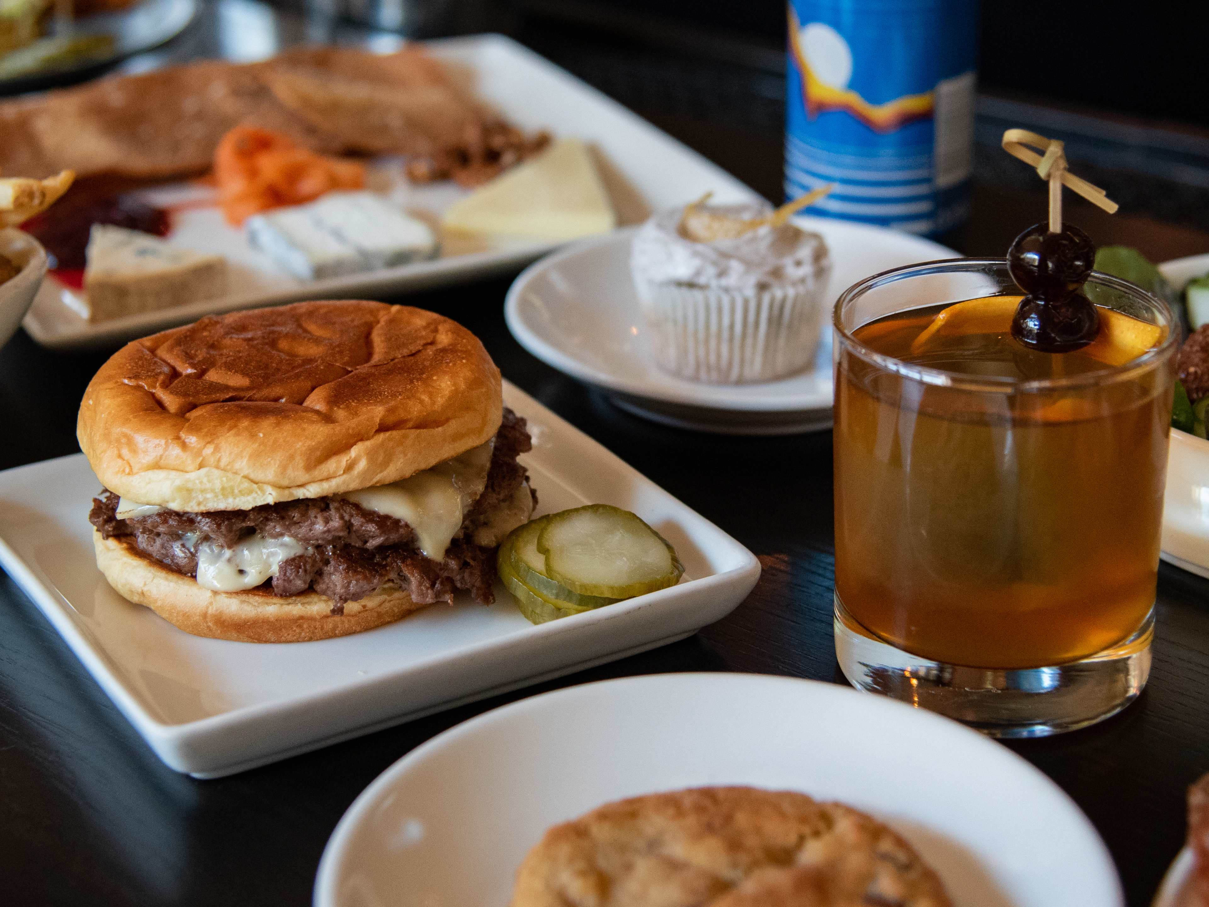 Spread of burgers, sides, and cocktails at Parlour
