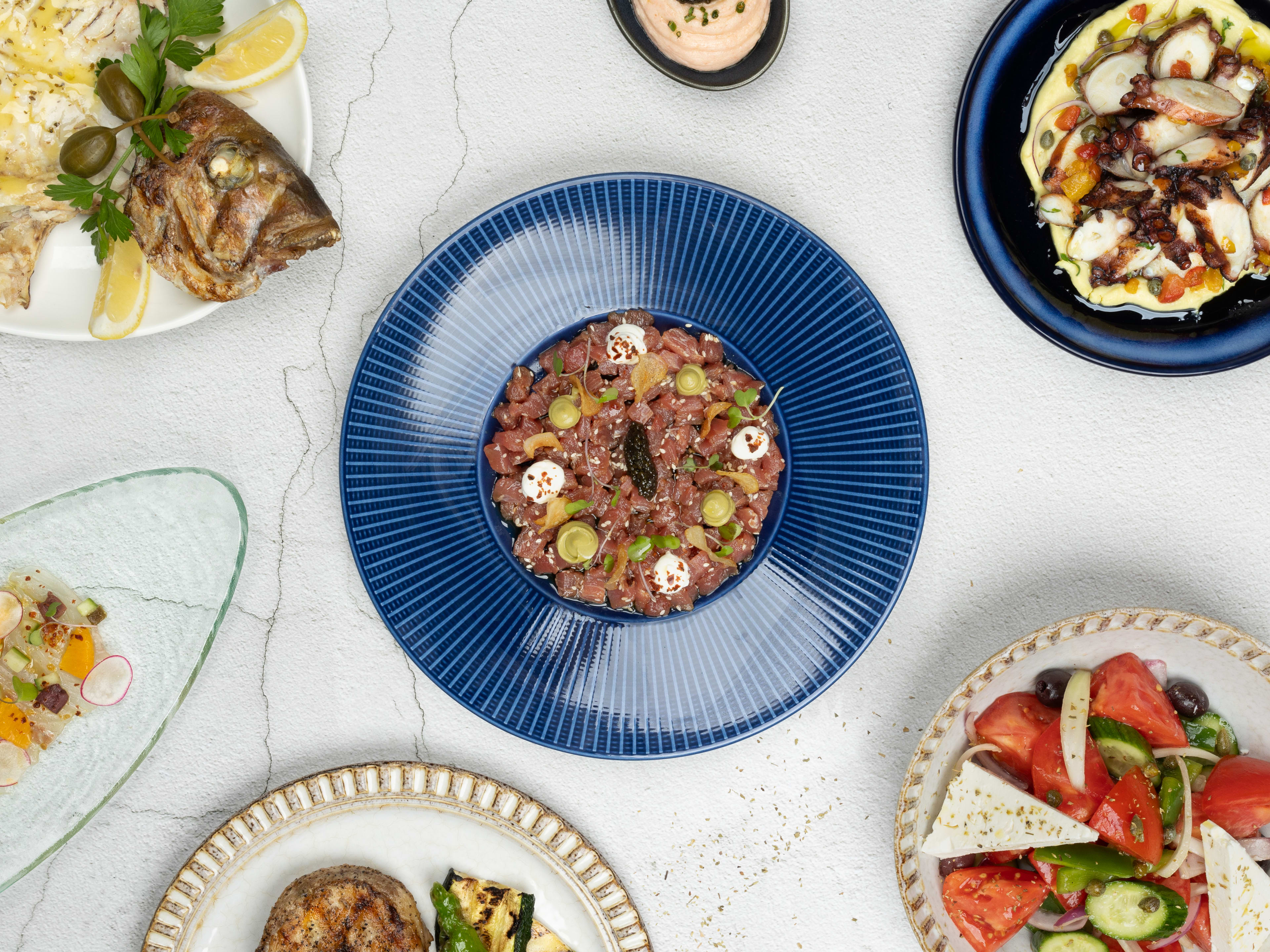 An assortment of salad, fish, and other upscale Greek food on a table.