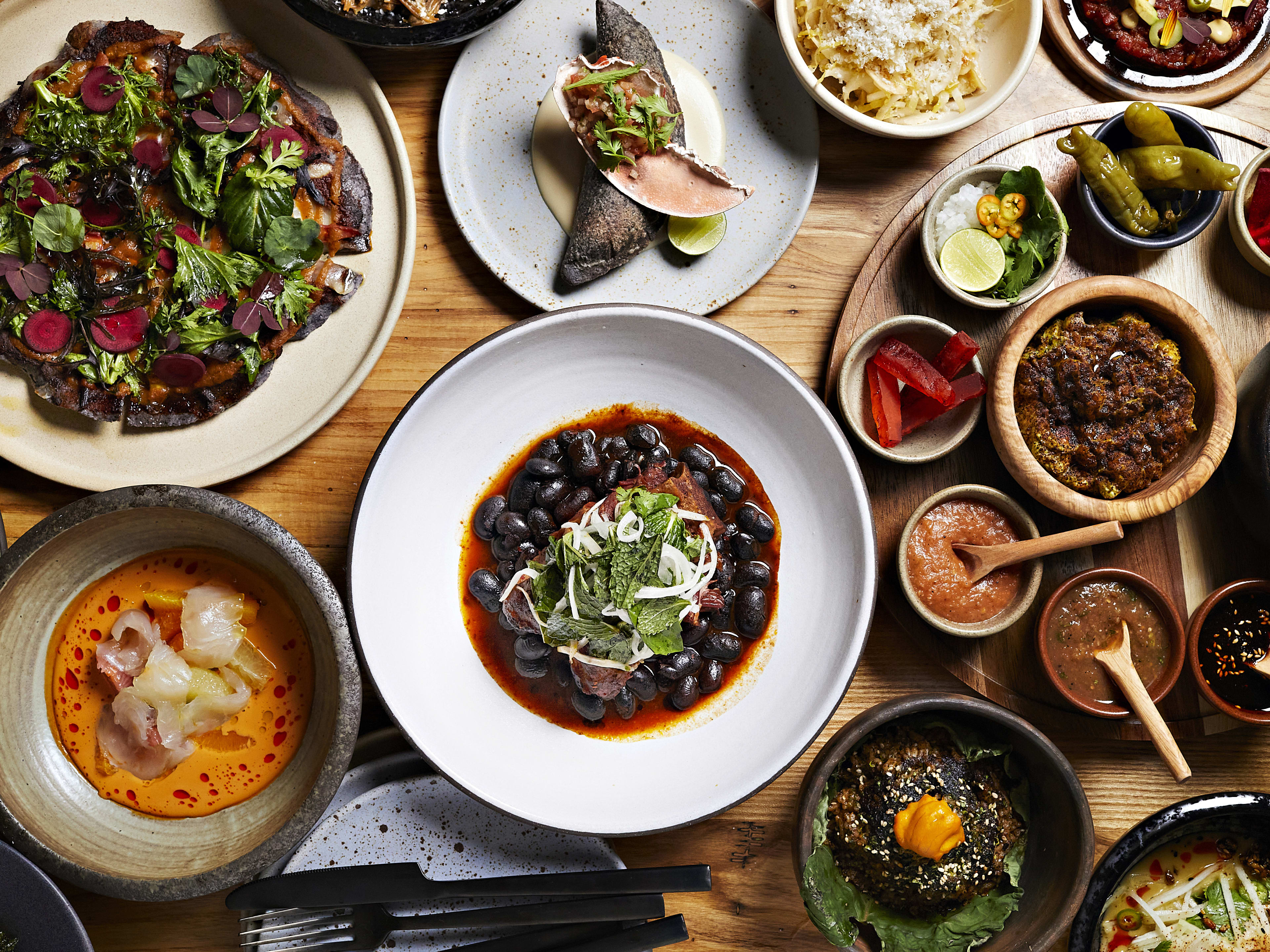 spread of mexican dishes such as beans, tostada, crudo, tetelas