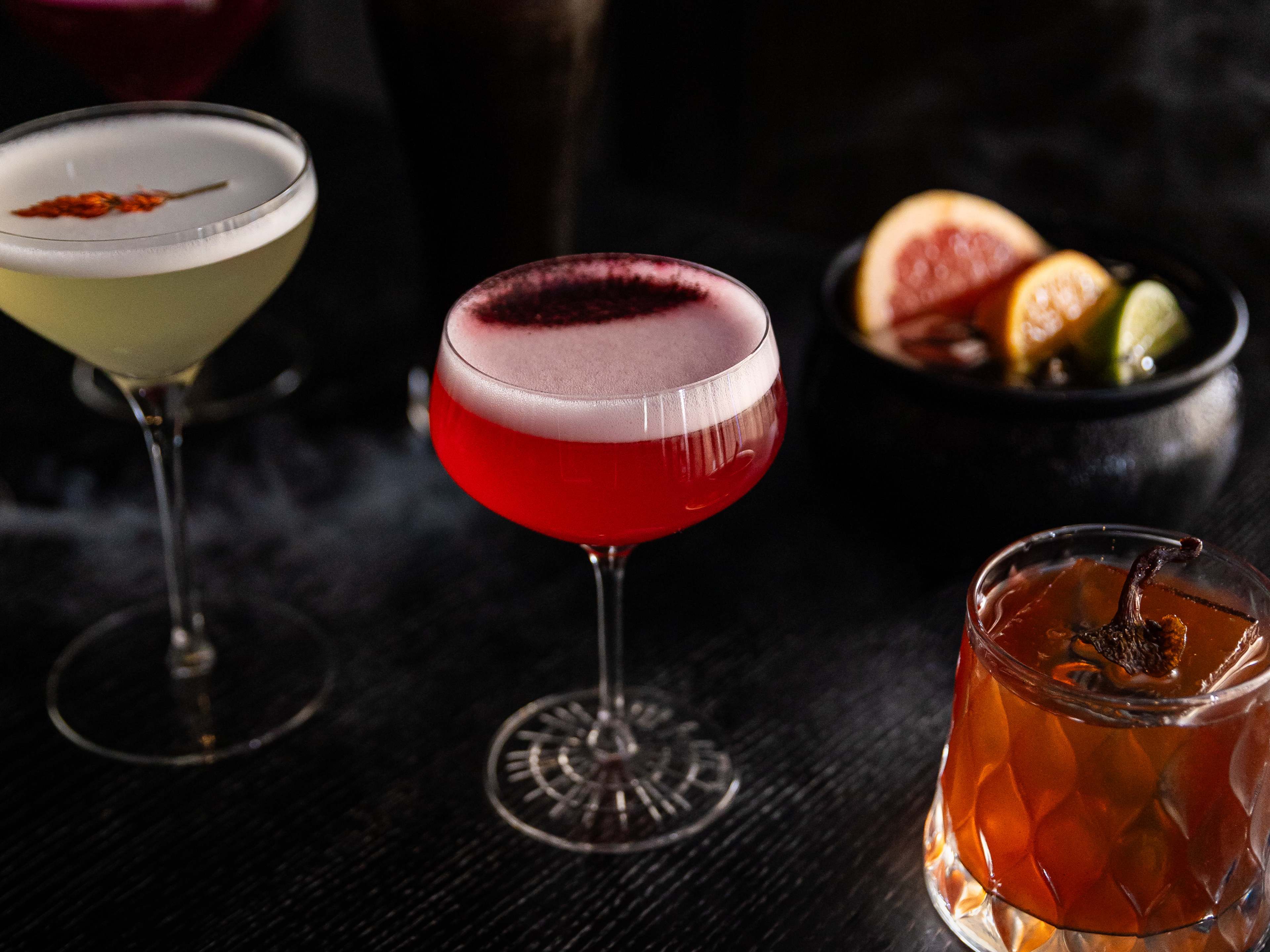 lineup of cocktails in different glasses on dark background