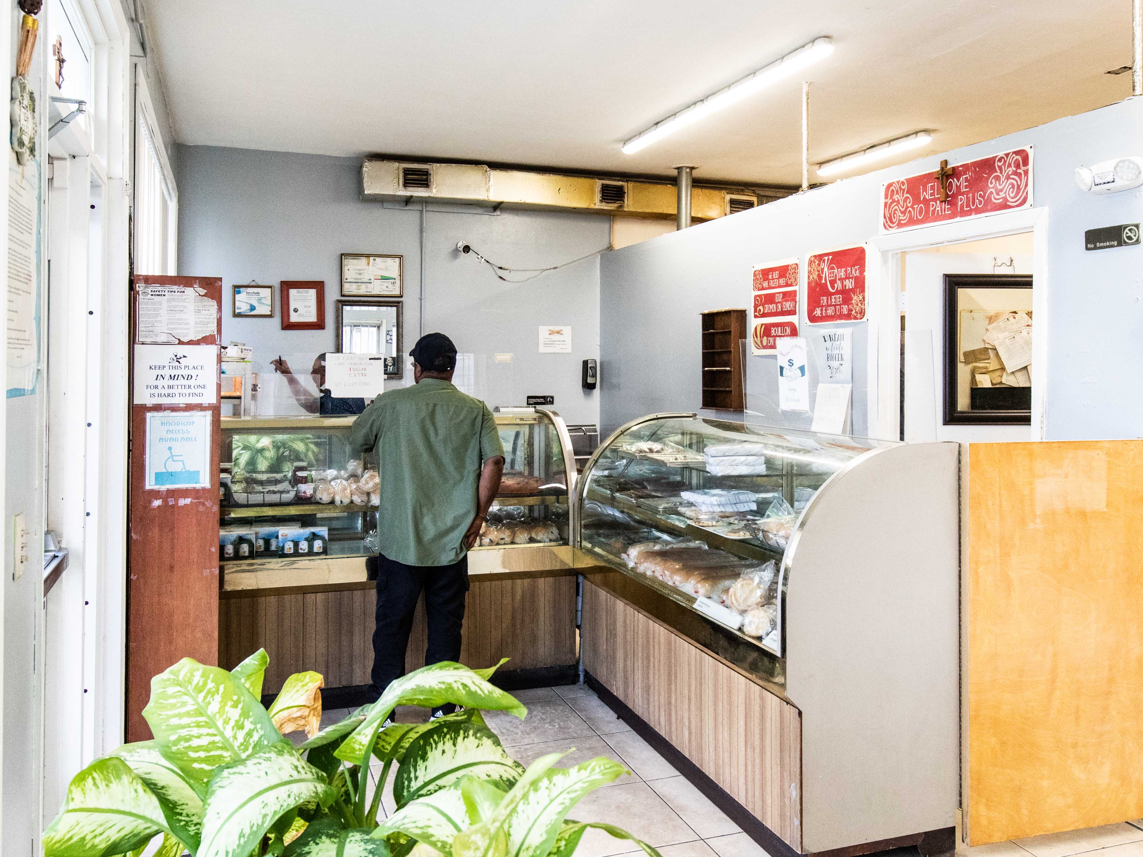 A man orders at a counter inside a small bakery.